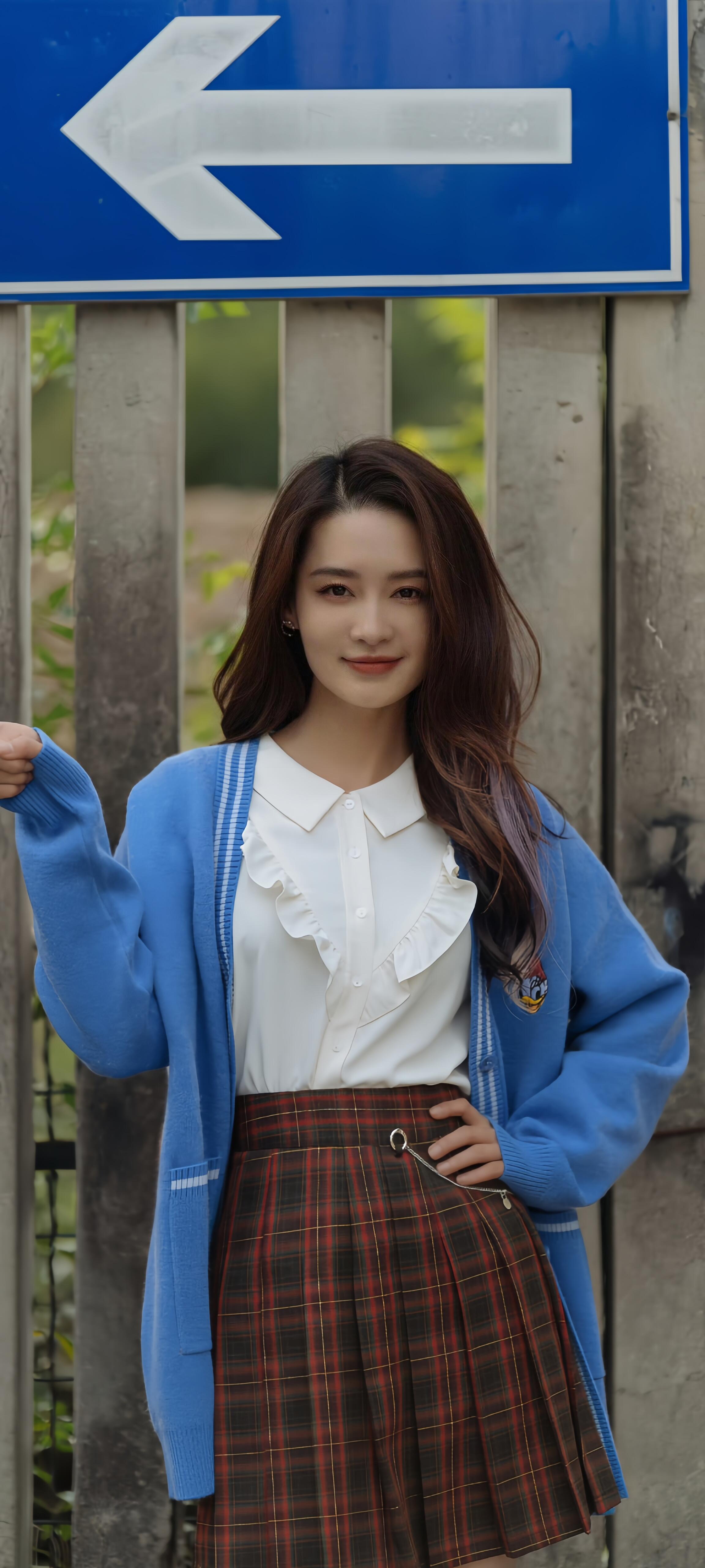 "李沁今天穿得好清新,蓝色开衫搭配格子裙,站在木栅栏前,笑容甜美