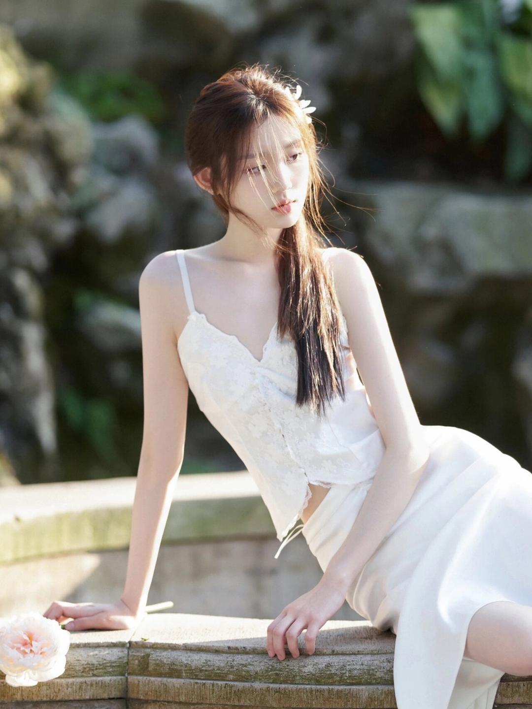 轻风拂过,阳光洒落,那位身穿白裙的女子侧身而坐,宛如一幅动人的画卷.