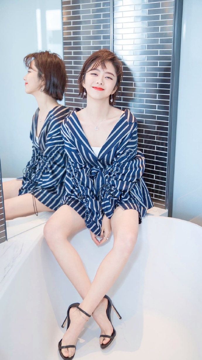 "谭松韵坐在洁白浴缸边缘,蓝白条纹裙衬映出夏日清新感,微笑中透出几