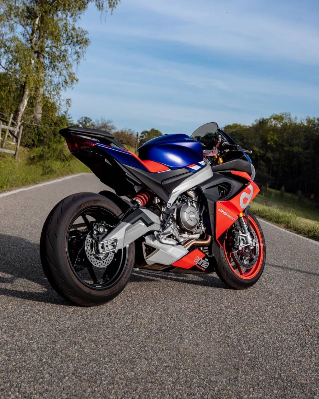 红蓝相间的摩托车,如火焰与冰川的交融,静静停在泥土路上,与周围的