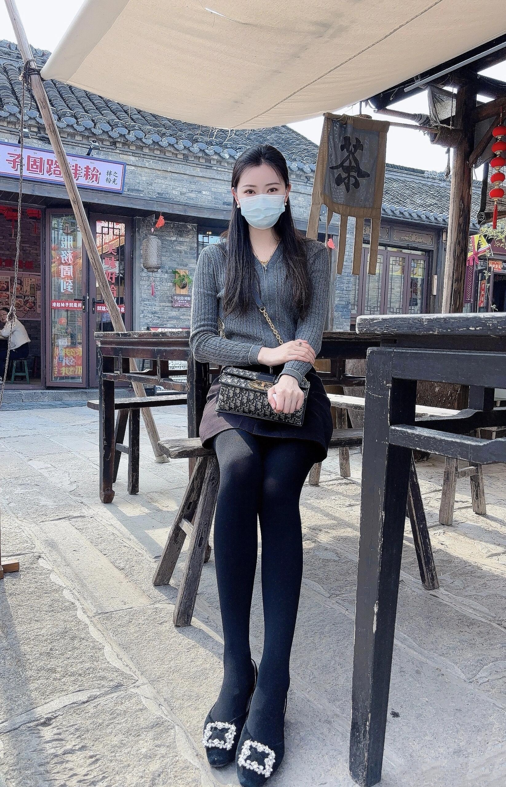 "  长椅上,她身着灰色毛衣与黑色短裙,脚踏一双别