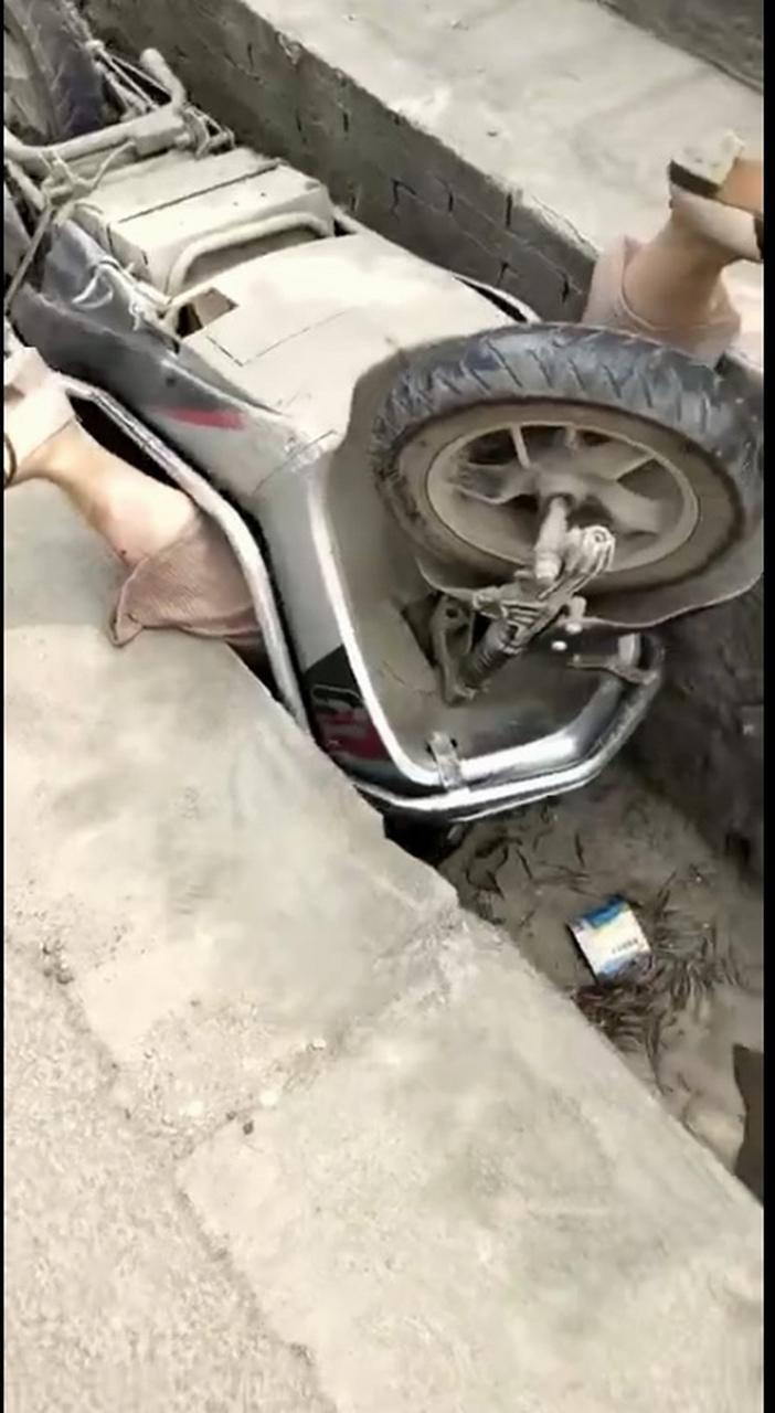 这个女子骑着两轮电动车摔翻在排水沟里,人翻车也翻,电动车还将女子死