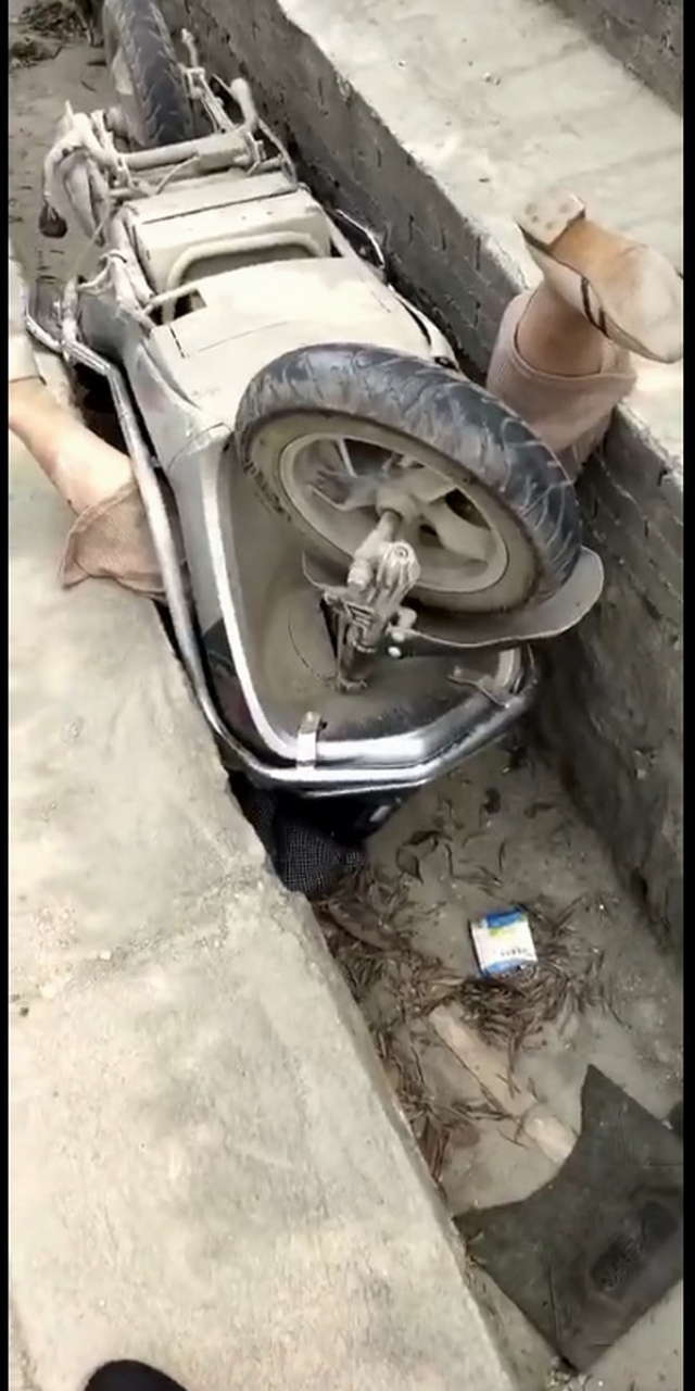 这个女子骑着两轮电动车摔翻在排水沟里,人翻车也翻,电动车还将女子死
