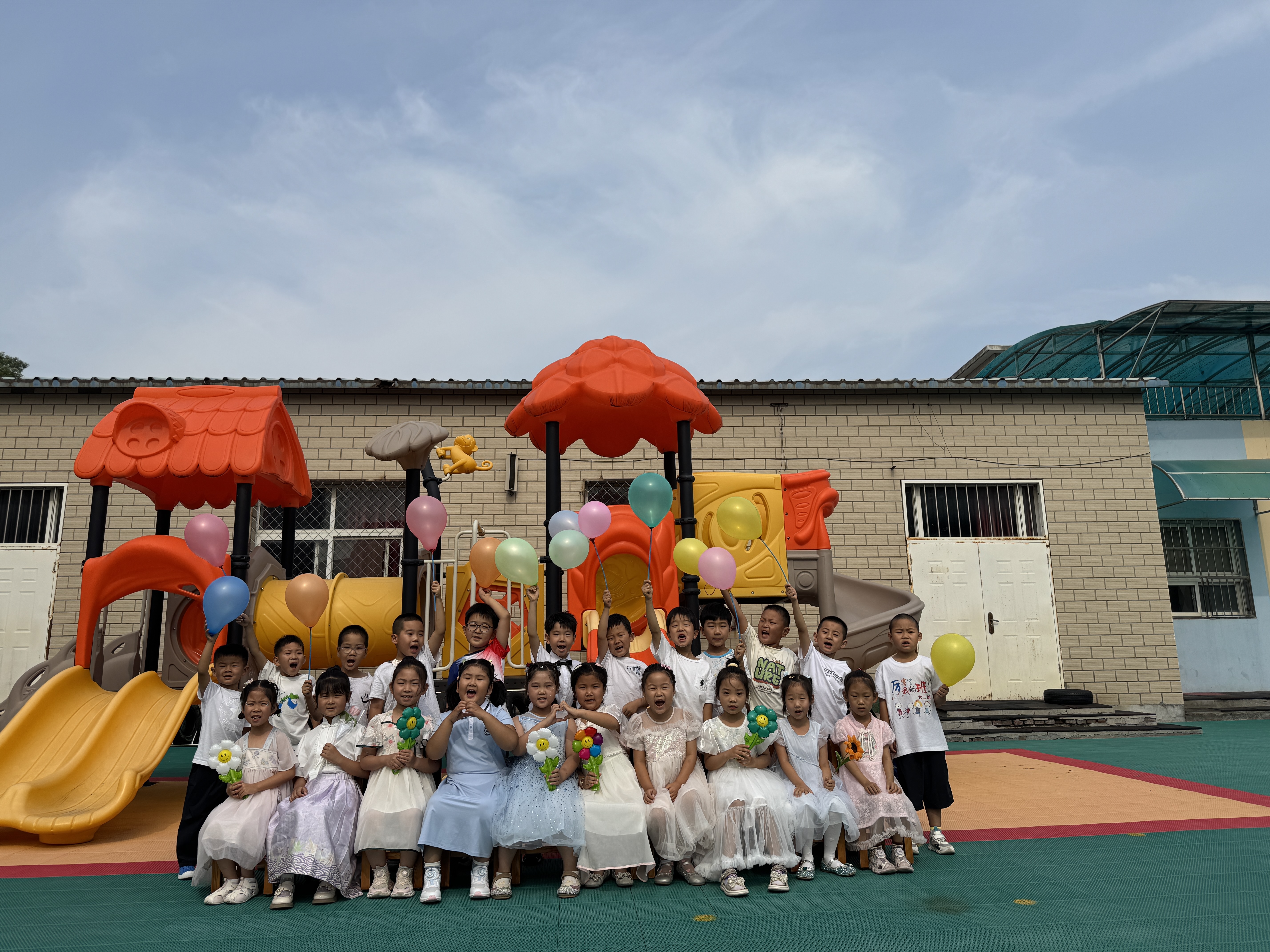 幼儿园的小朋友们和老师们一起在彩色的滑梯和房子前留下了珍贵的