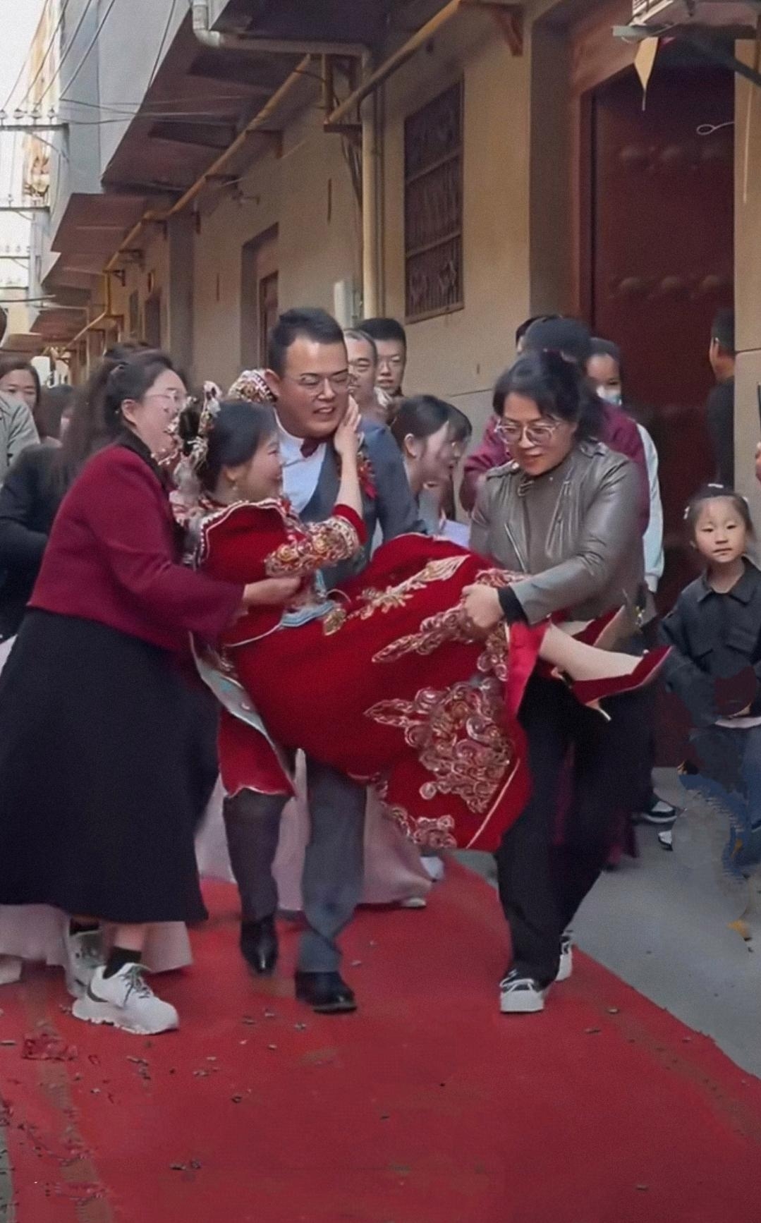 按习俗新娘脚不能沾地,新郎大概没提前练体能,抱新娘时一个踉跄差点脱