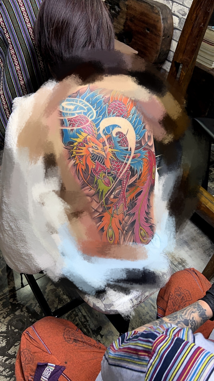 "背后醒目的凤凰纹身,色彩鲜艳,展翅飞翔于云端星辰之间,仿佛诉说着一