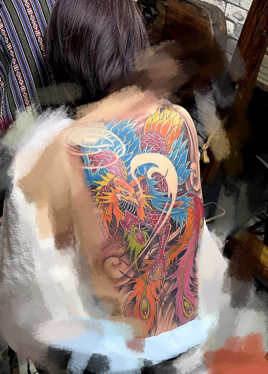 "背后醒目的凤凰纹身,色彩鲜艳,展翅飞翔于云端星辰之间,仿佛诉说着一