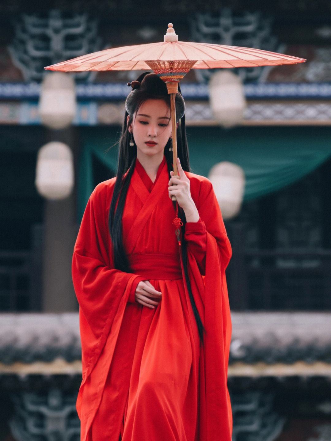 身穿红色古装,手持一把油纸伞,仿佛从画中走出来一般