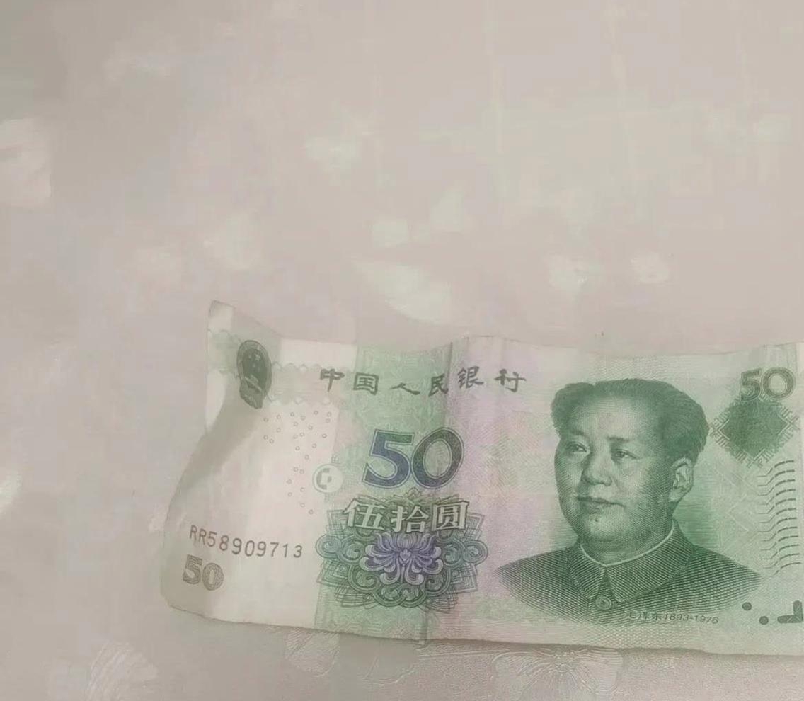女子顺手就掏出一张50元纸币,递给卖肉的摊主