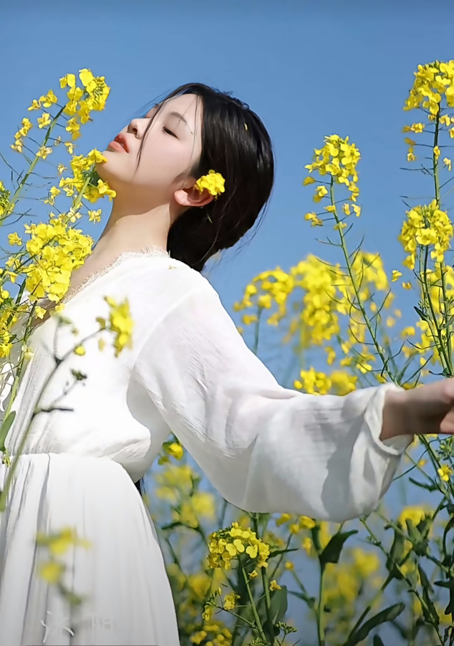 油菜花间的草帽少女  蓝天下,白云悠悠,油菜花地里,站着一位草帽女子.