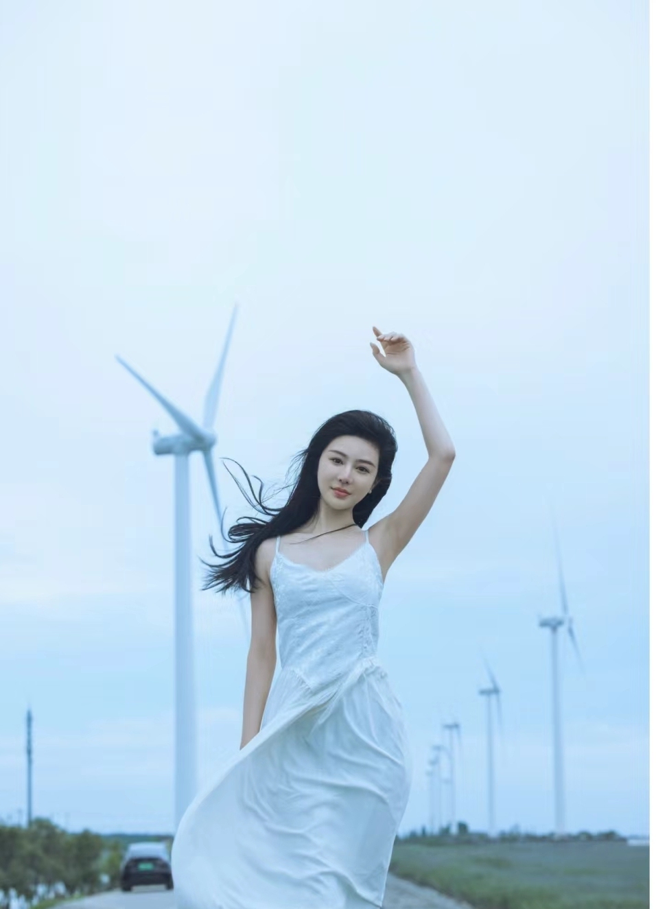 这位仙女般的女子身穿白色长裙,手执草帽,仿佛正在聆听风的低语.