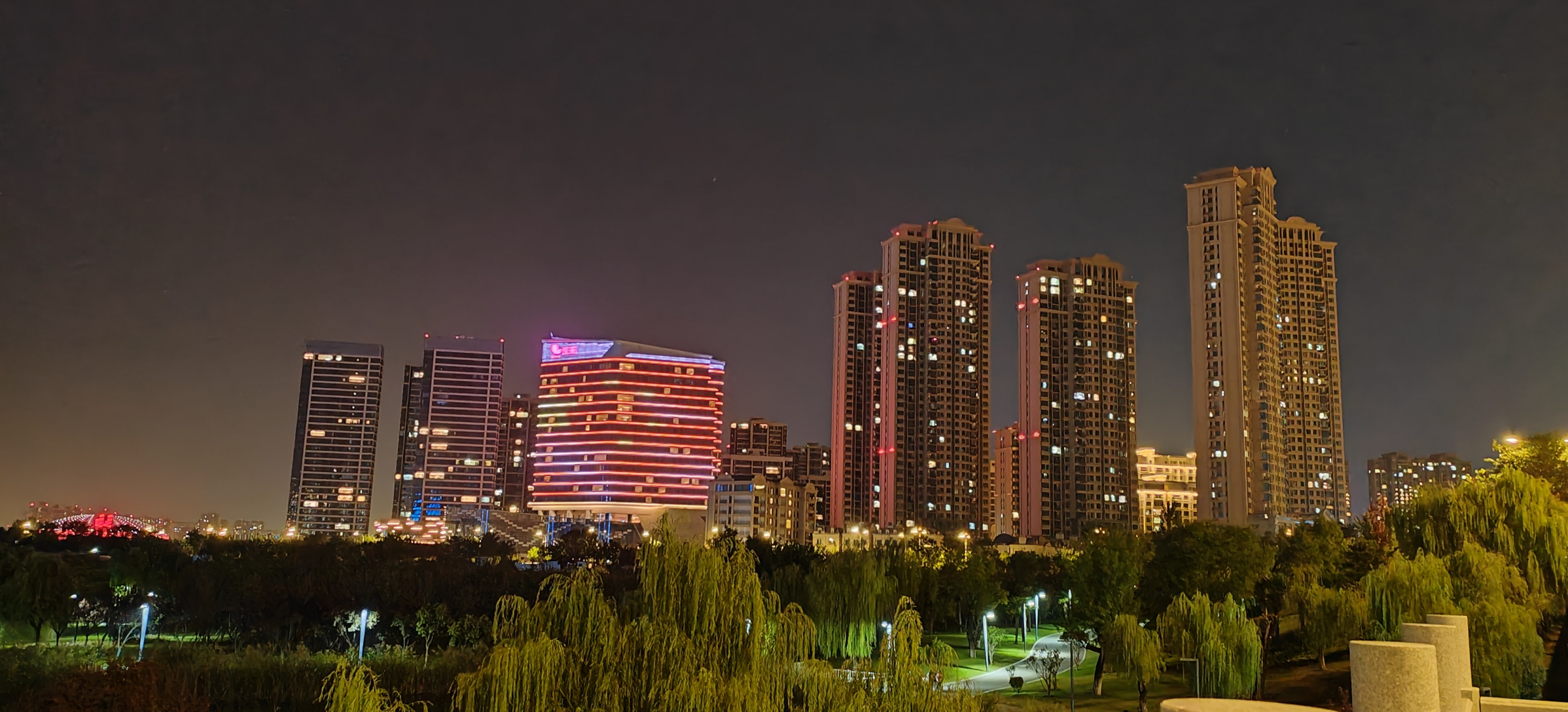 78夜幕降临,城市灯火闪烁,高楼大厦在夜色中更显壮观,树木轻轻摇曳