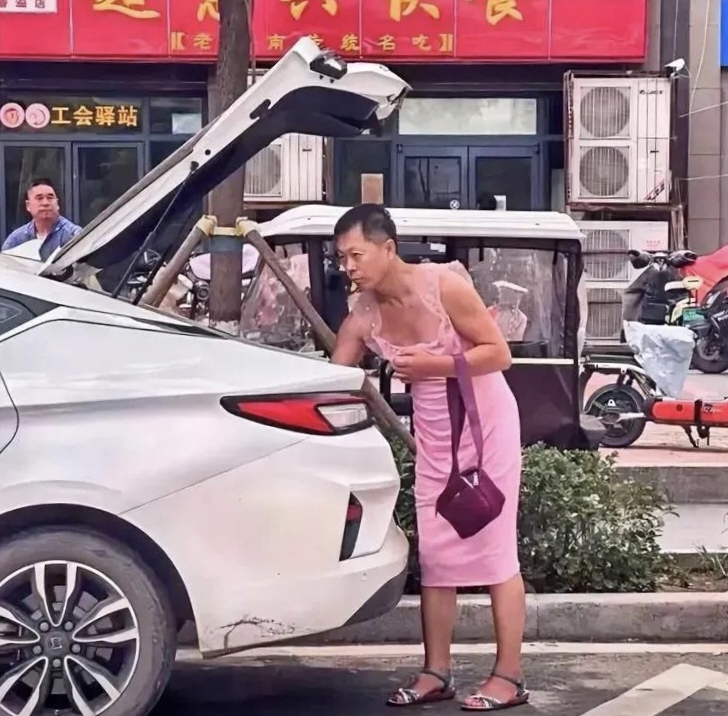 在街边看到一个奇葩男人,身穿一件粉红色的连衣裙,平底凉鞋,手挎一个