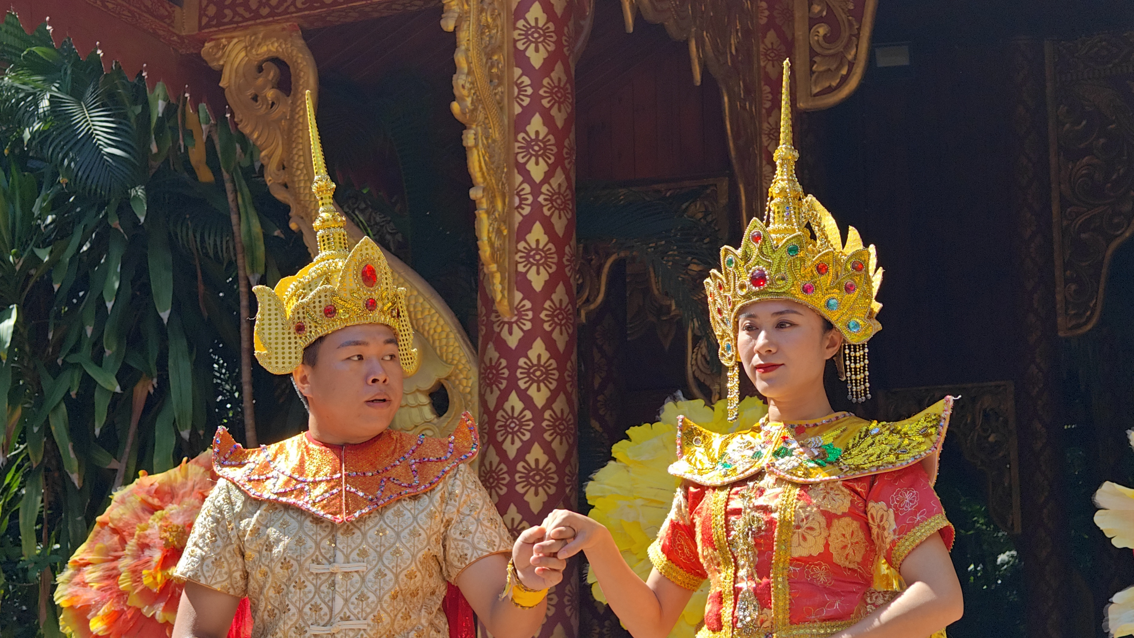 舞台上,一对男女舞者正在表演泰国传统舞蹈,他们的头上戴着金色的帽子