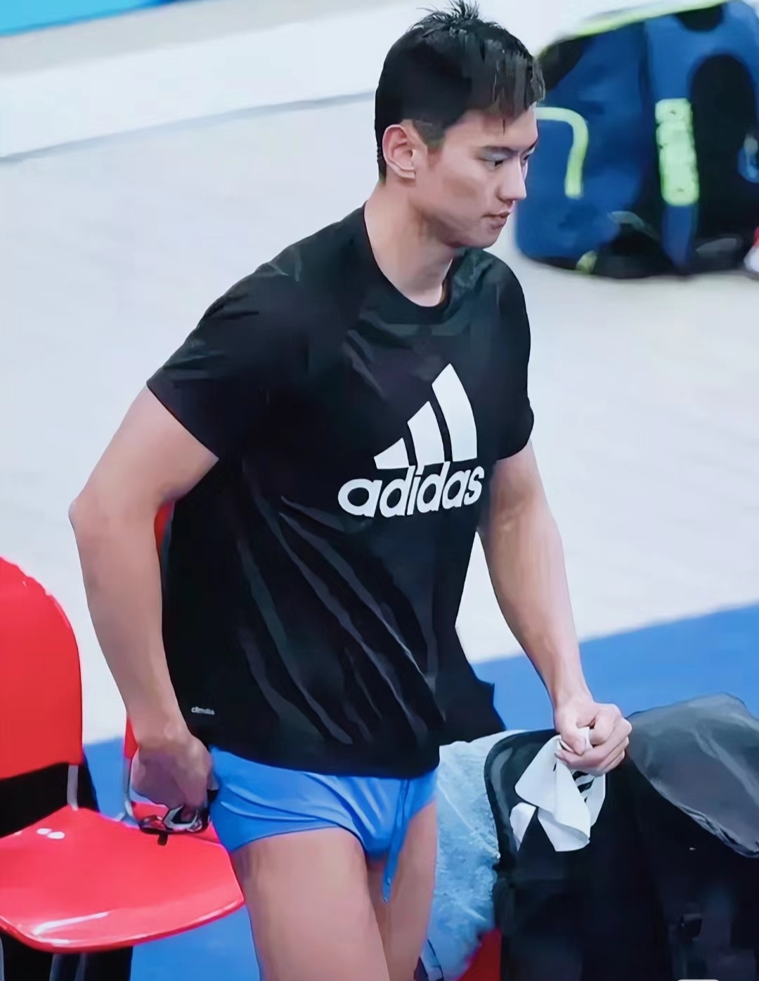 宁泽涛身穿adidas黑t,活力十足地走向镜头,左手紧握红色椅子一角,蓝色