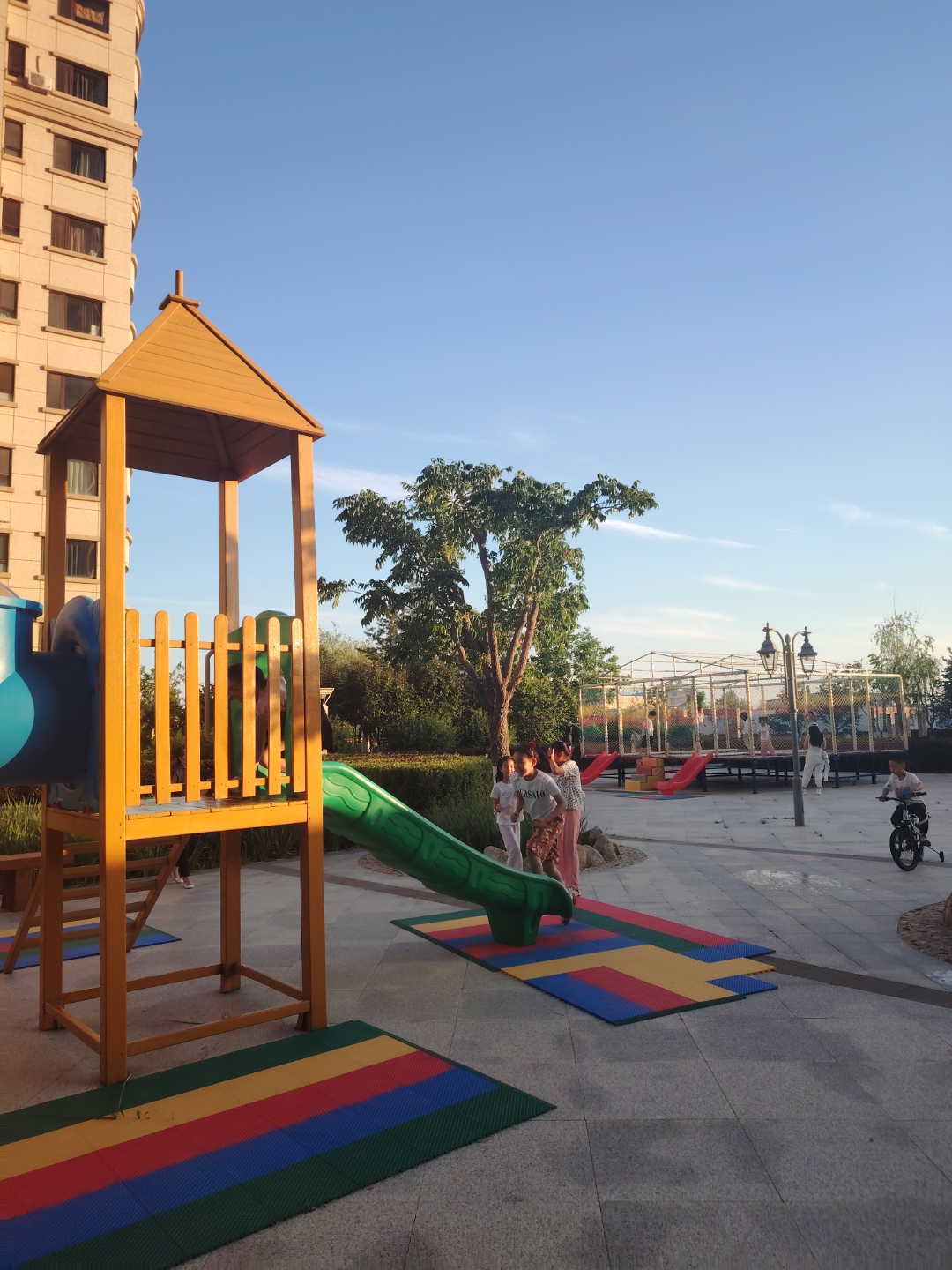 夕阳西沉,晚霞满天,小区里蹦床上的孩子们欢腾雀跃