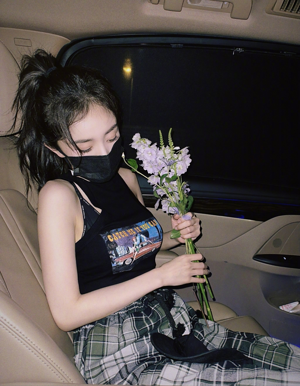 杨幂戴着黑口罩,手上还拿着花儿,坐在车里,依旧显得特别漂亮.