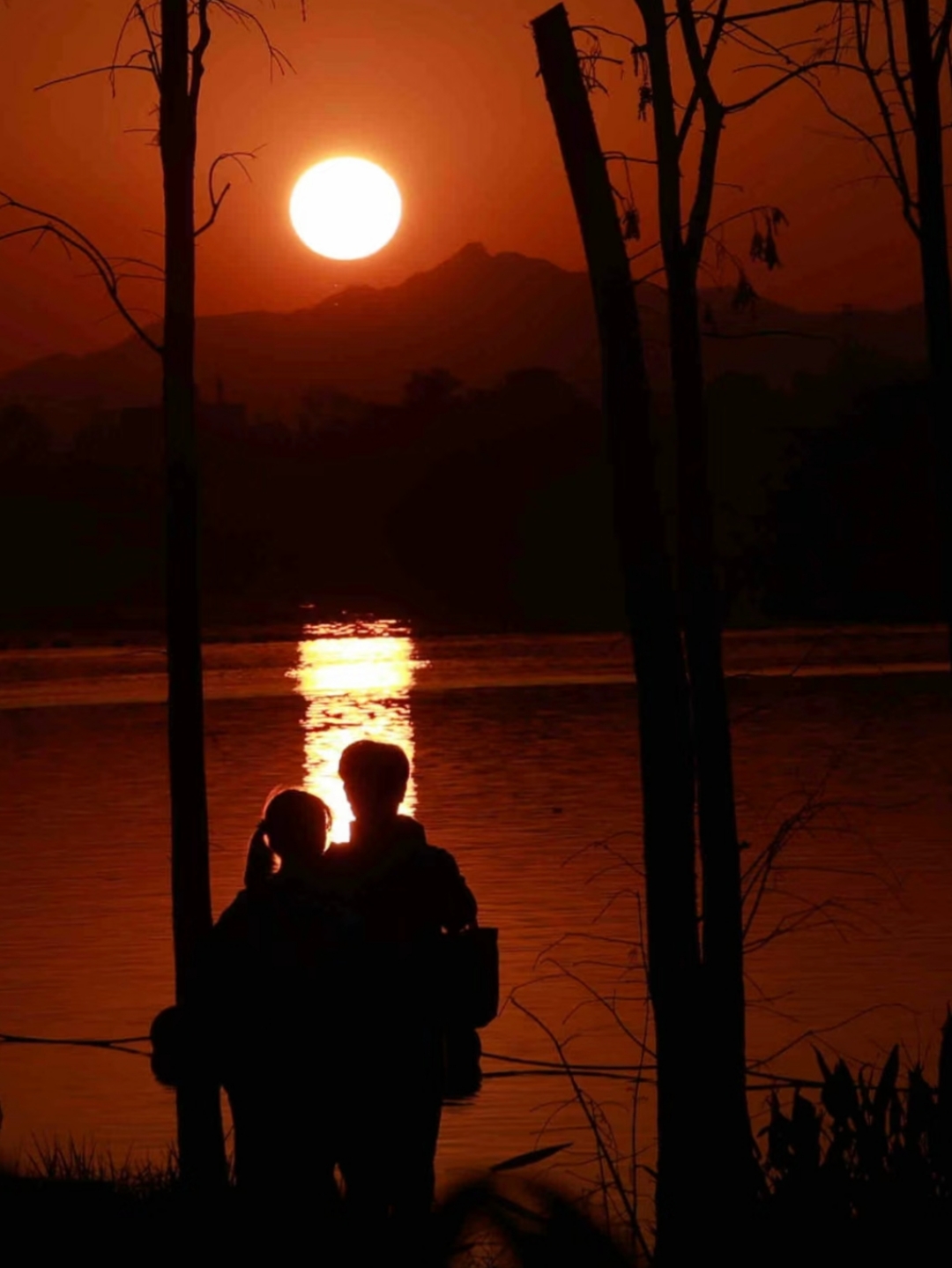 湖面上的夕阳,天空中的浪漫, 一对情侣静静地凝视