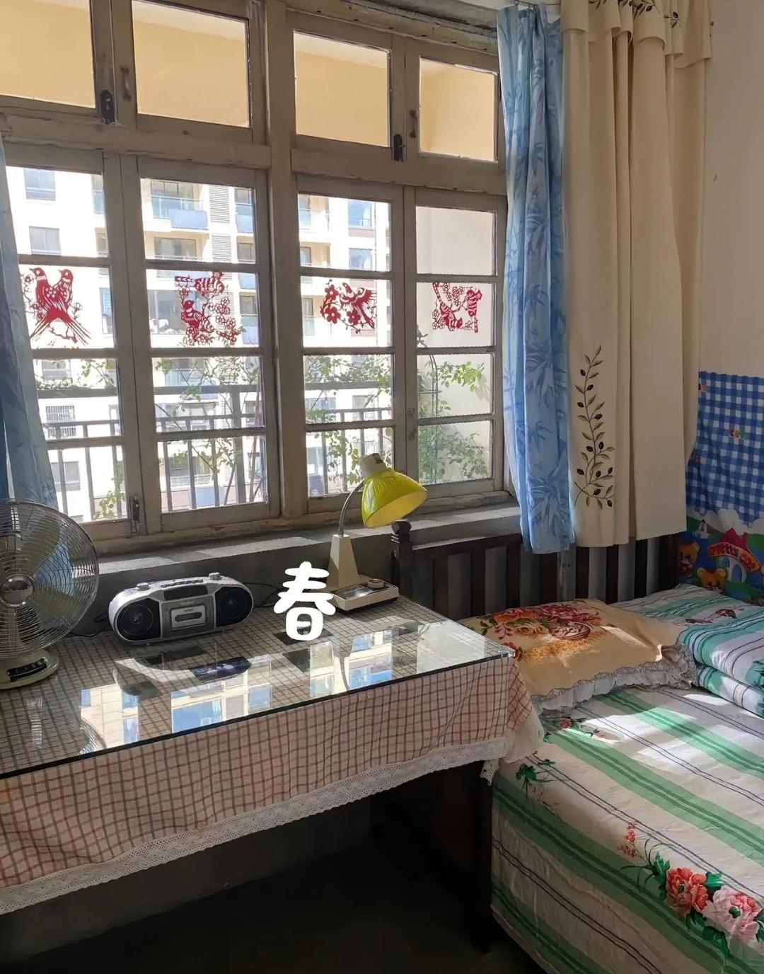 这是八十年代一个小姐姐房间,里面摆放着简单的木质家具,碎花的床单