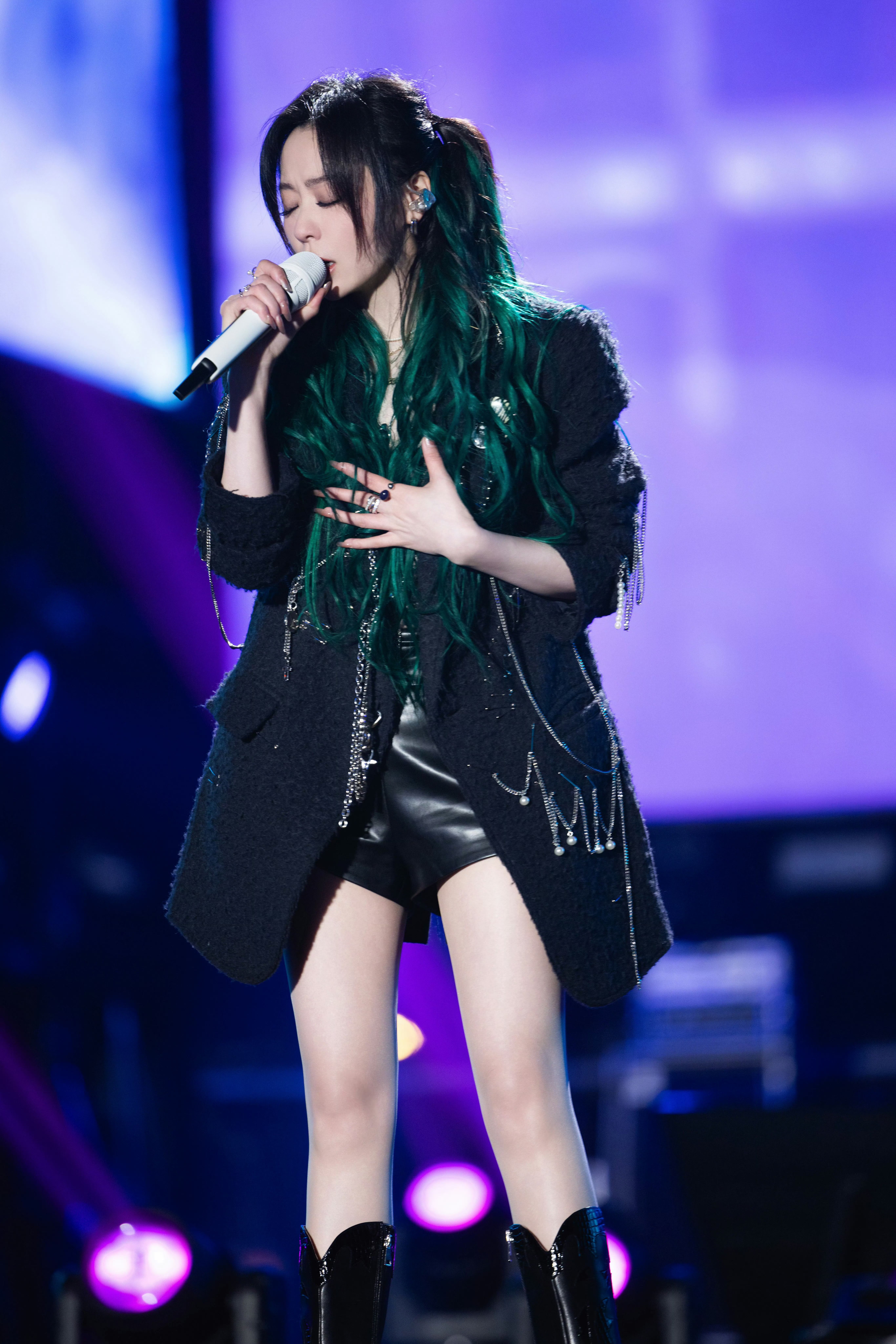 她穿着皮衣短裤,搭配黑靴,长发随性披散,自信地站在舞台上#张靓颖