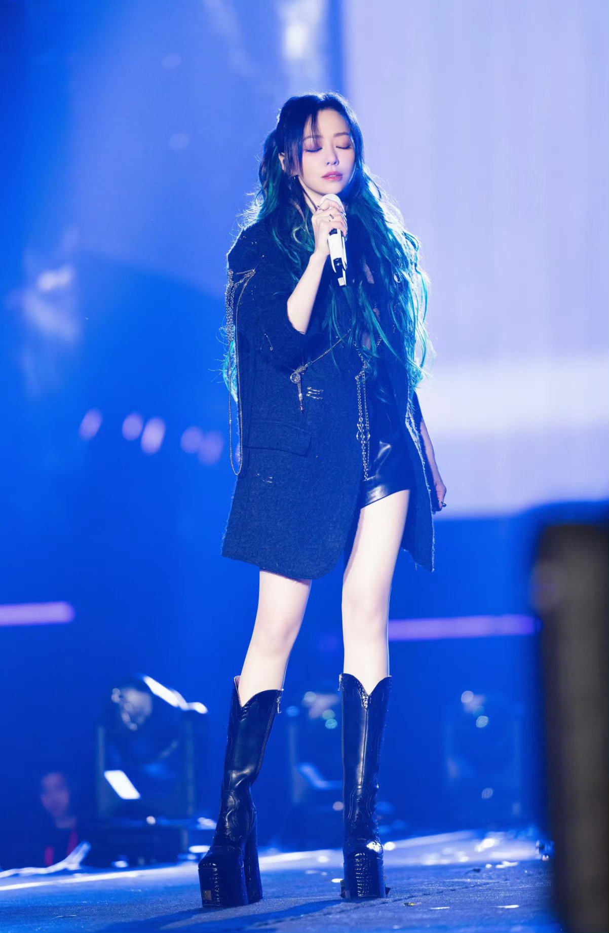 她穿着皮衣短裤,搭配黑靴,长发随性披散,自信地站在舞台上#张靓颖