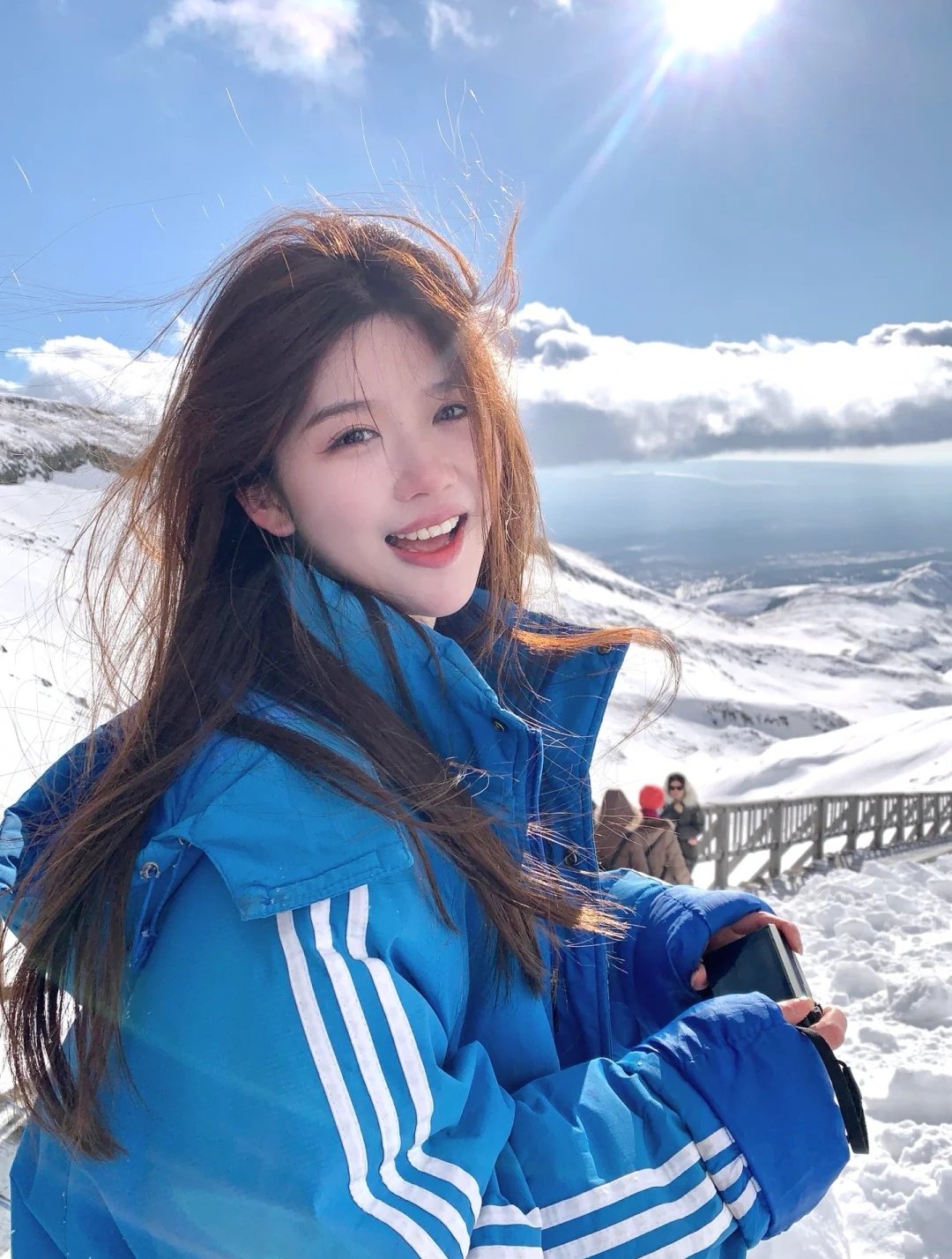 冬天的早晨,雪花飘飘,一个穿着蓝色外套的小女孩在雪地里玩耍