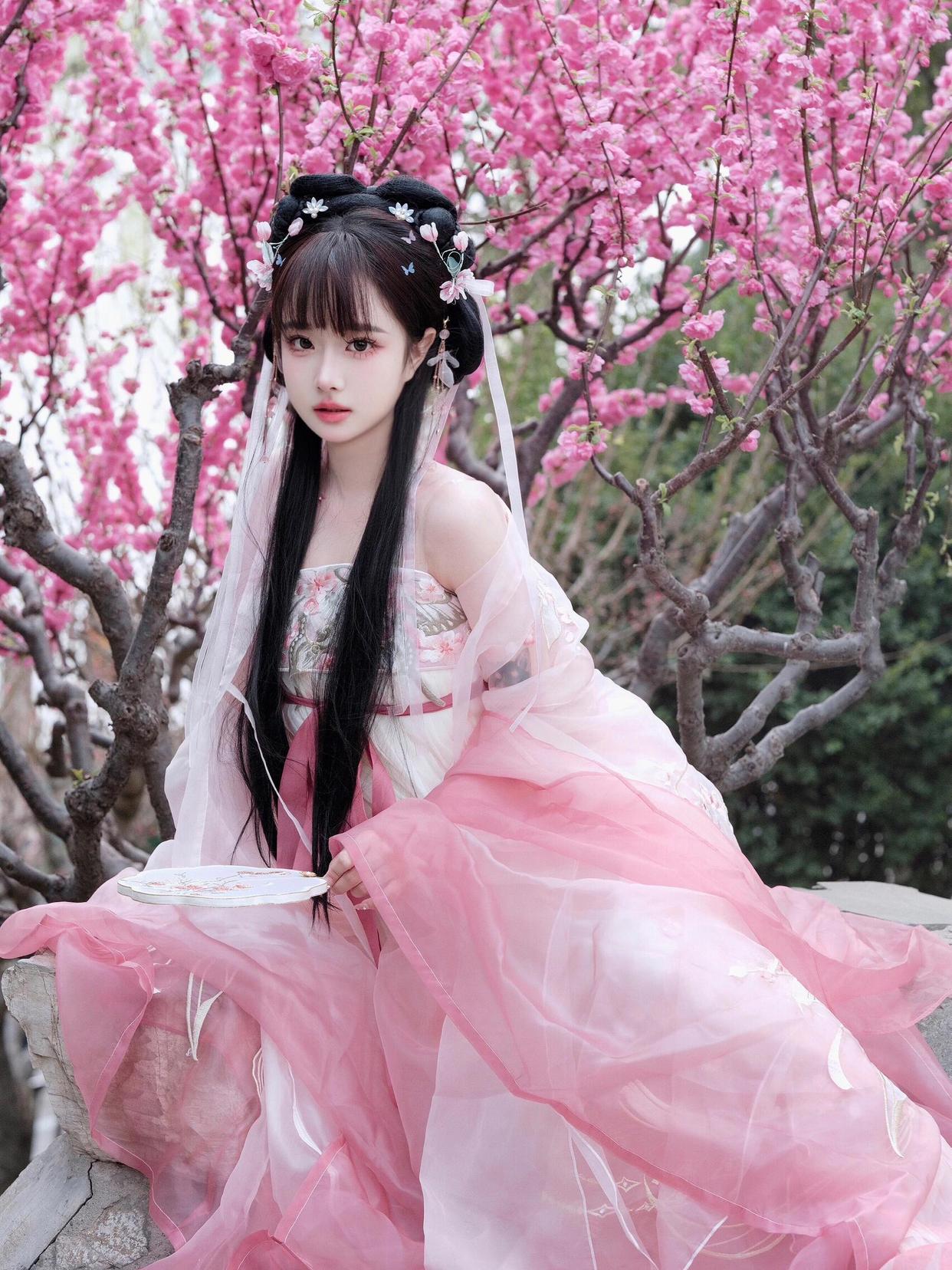 她身着粉色汉服,衣袂飘飘,仿佛穿越千年时光,与这春光共舞.