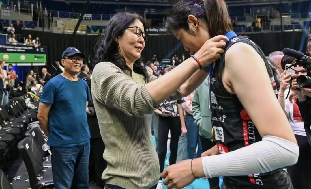 郎导的丈夫王育成站在一边,默默看着郎平和朱婷拍照,互戴金牌,摄影师