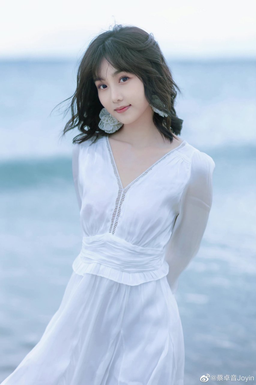 演员蔡卓音,一身白色连衣裙,在海边蓝色背景的衬托下,清新脱俗#蔡卓音
