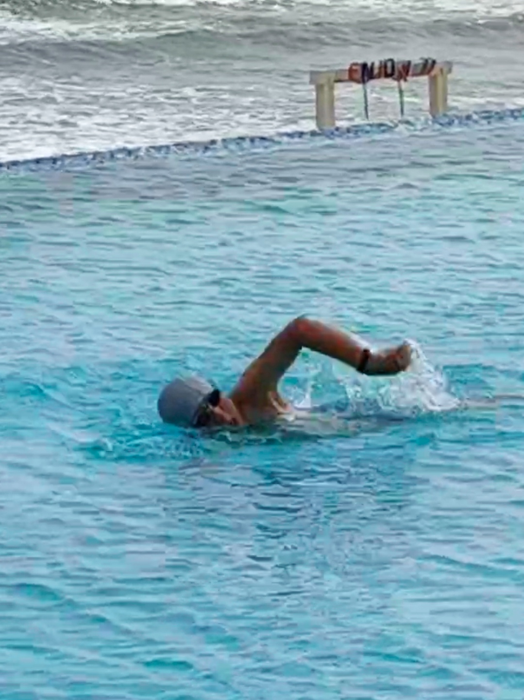 根据描述生成一位穿白色短裤在多人泳池中游泳的人物摄影图乒愣 11