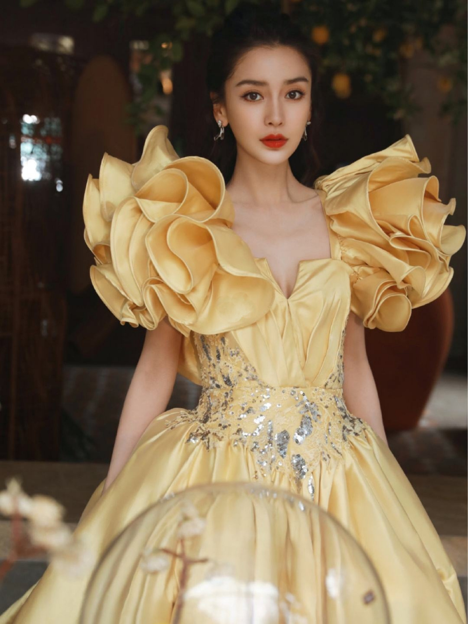 angelababy这件黄色礼服裙繁复华贵,肩部的夸张花朵设计显得baby的脸