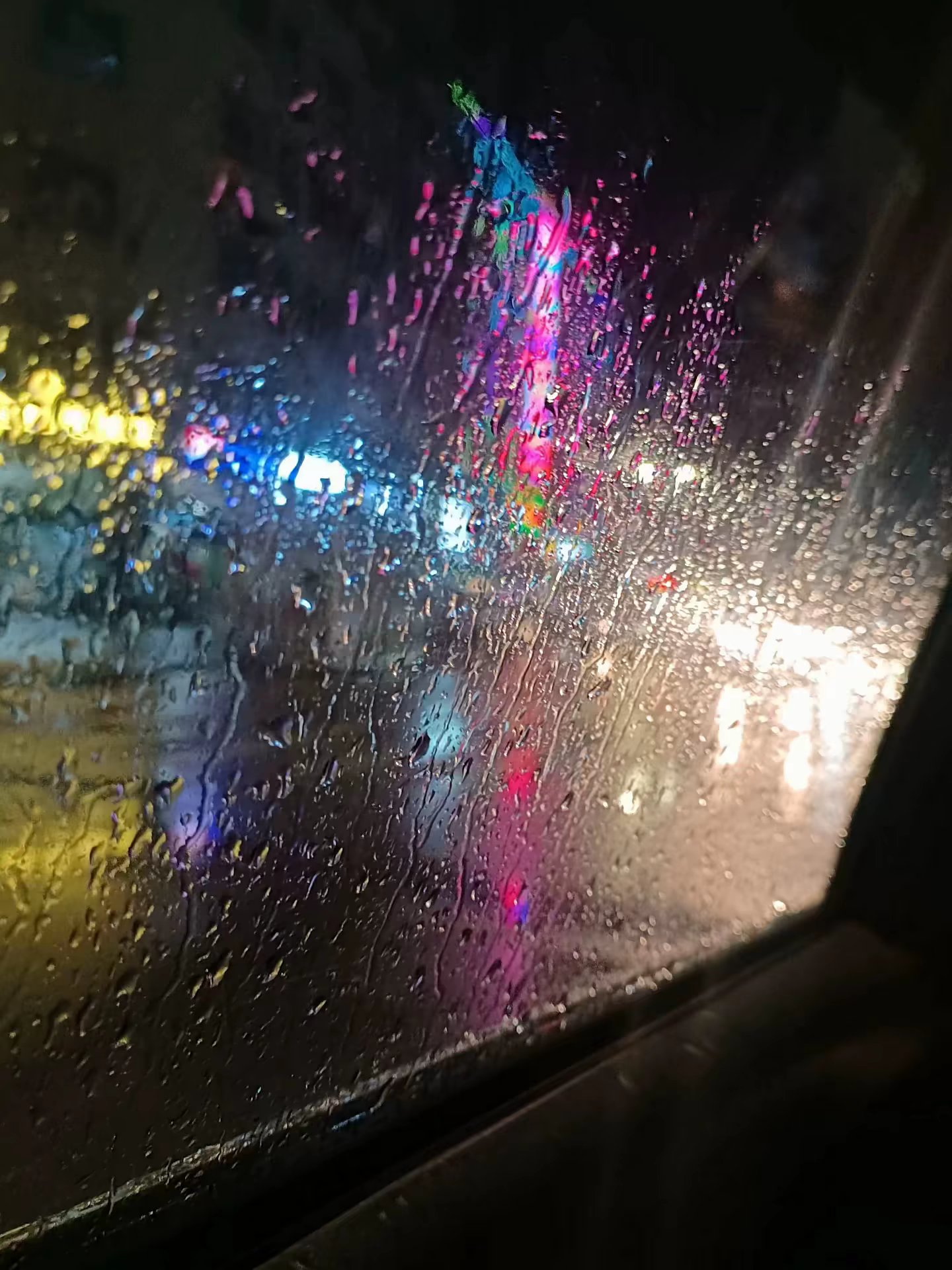 雨夜车窗上的倒影,映出街灯的温暖光芒,仿佛整个城市都被雨滴隔离开来