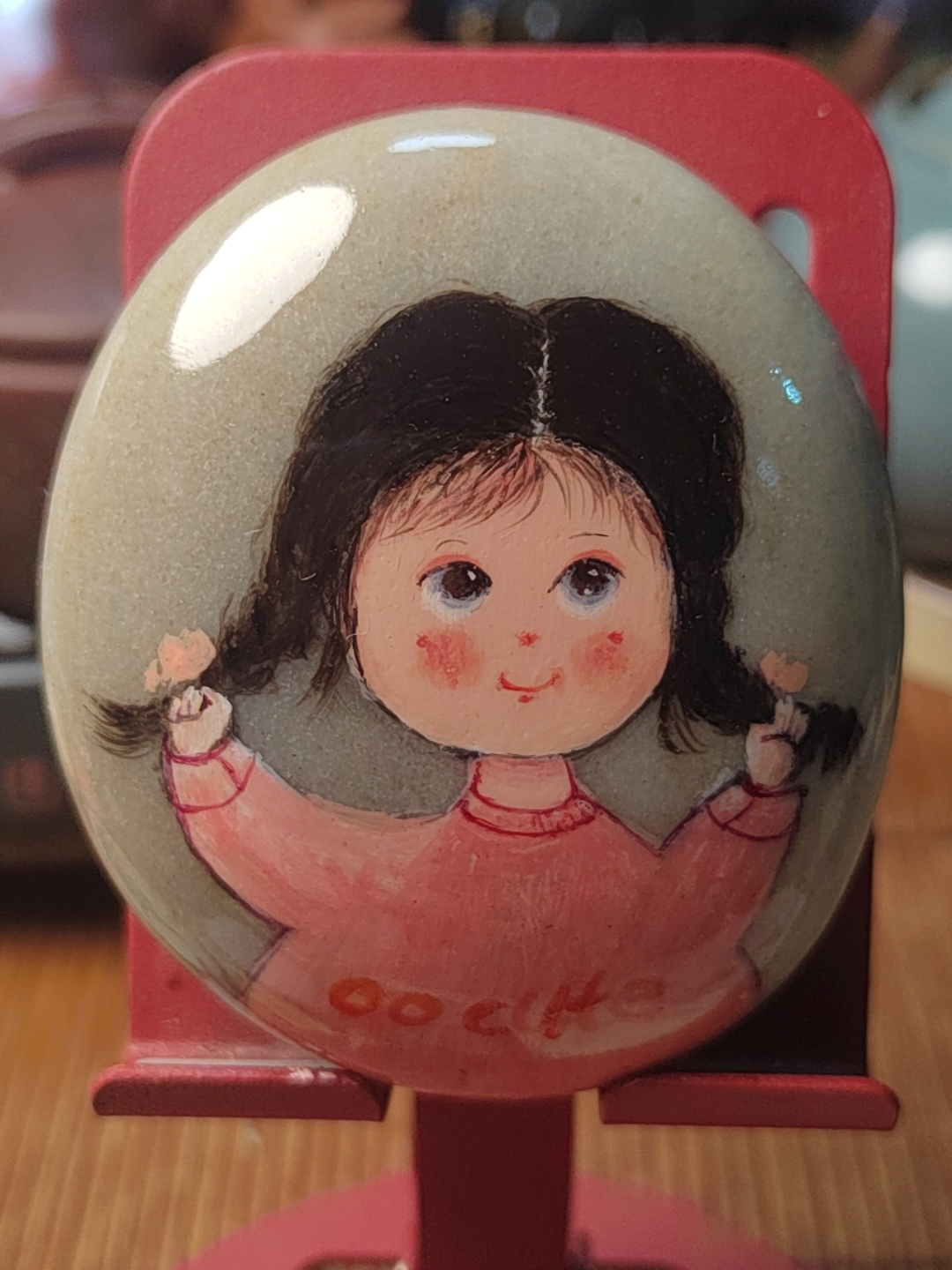 在普通的石头上 绘出三个童真小萌娃 绿衣萌娃戴童趣发箍 粉衣小可爱