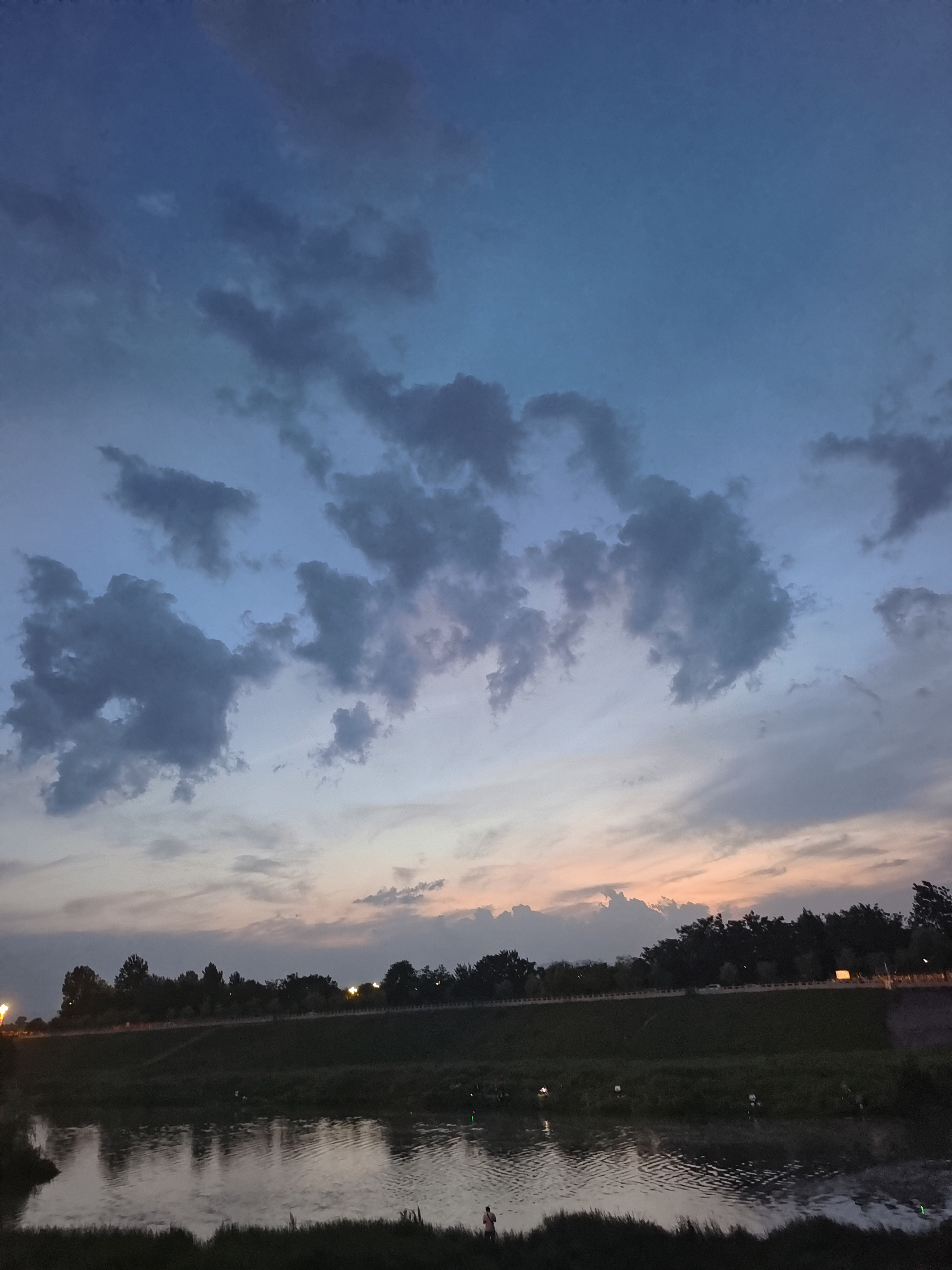 傍晚时分,天空如一幅层次分明的蓝灰画卷,梦幻般的云朵悠然漂浮.