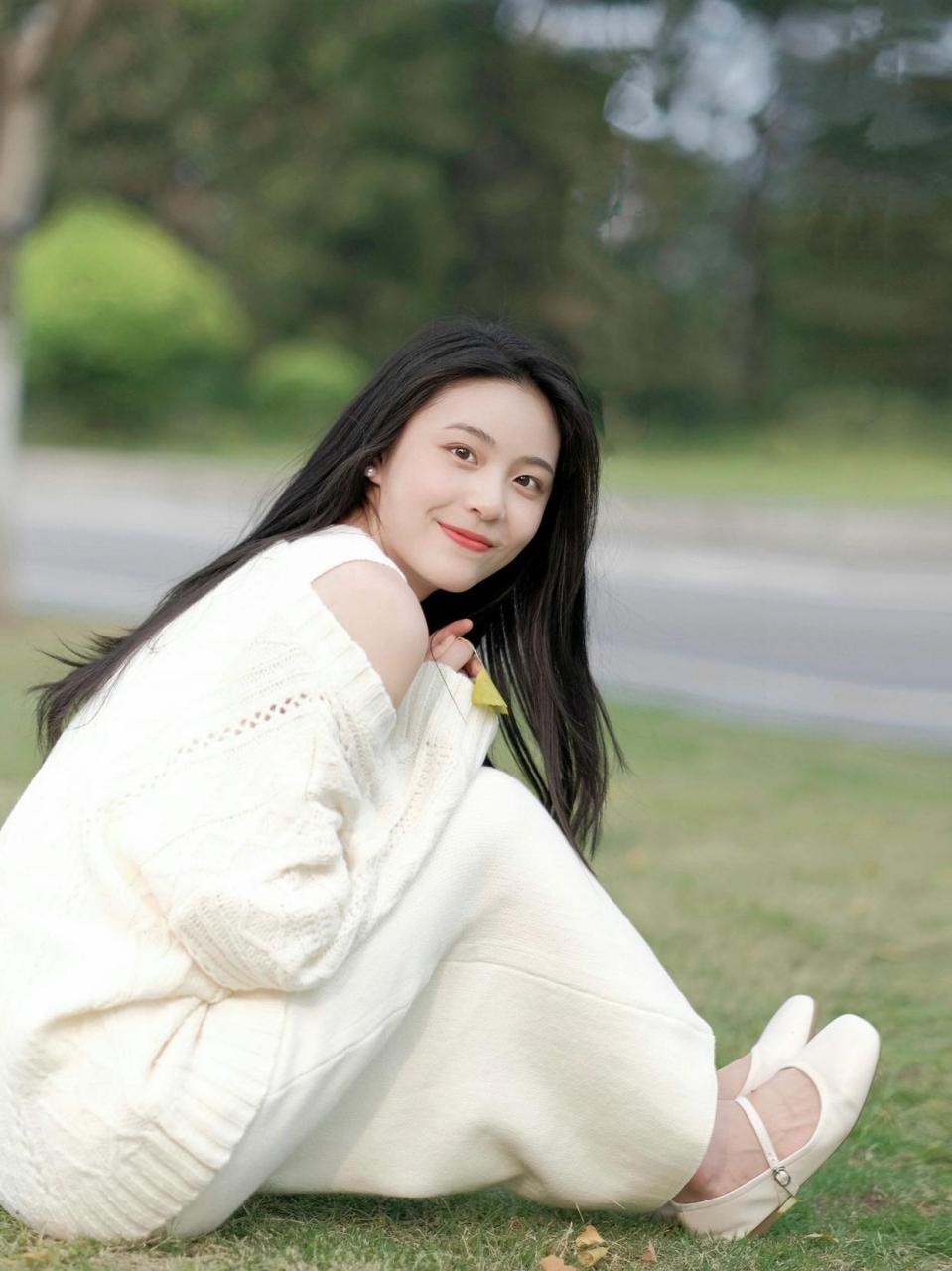 "温暖的阳光下,一位优雅的女子站在翠绿的草坪上,微笑着向世界展示她