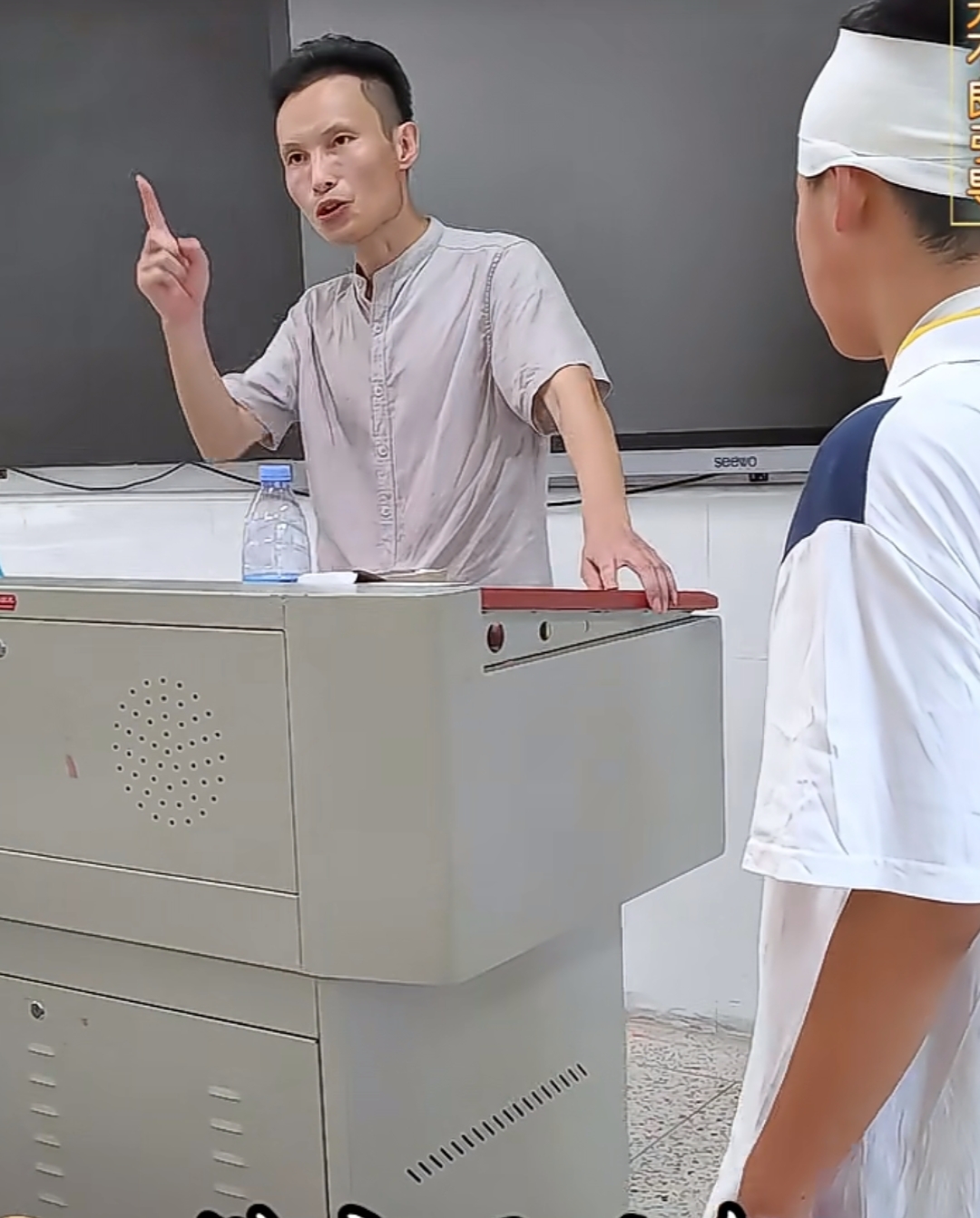 学生头上包着布巾,一瘸一拐走进教室,迟到了,老师问