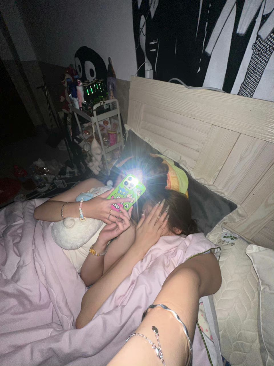 夜晚的卧室内,躺在床上,手拿手机,头戴发箍,粉色的床单,温馨而静谧.