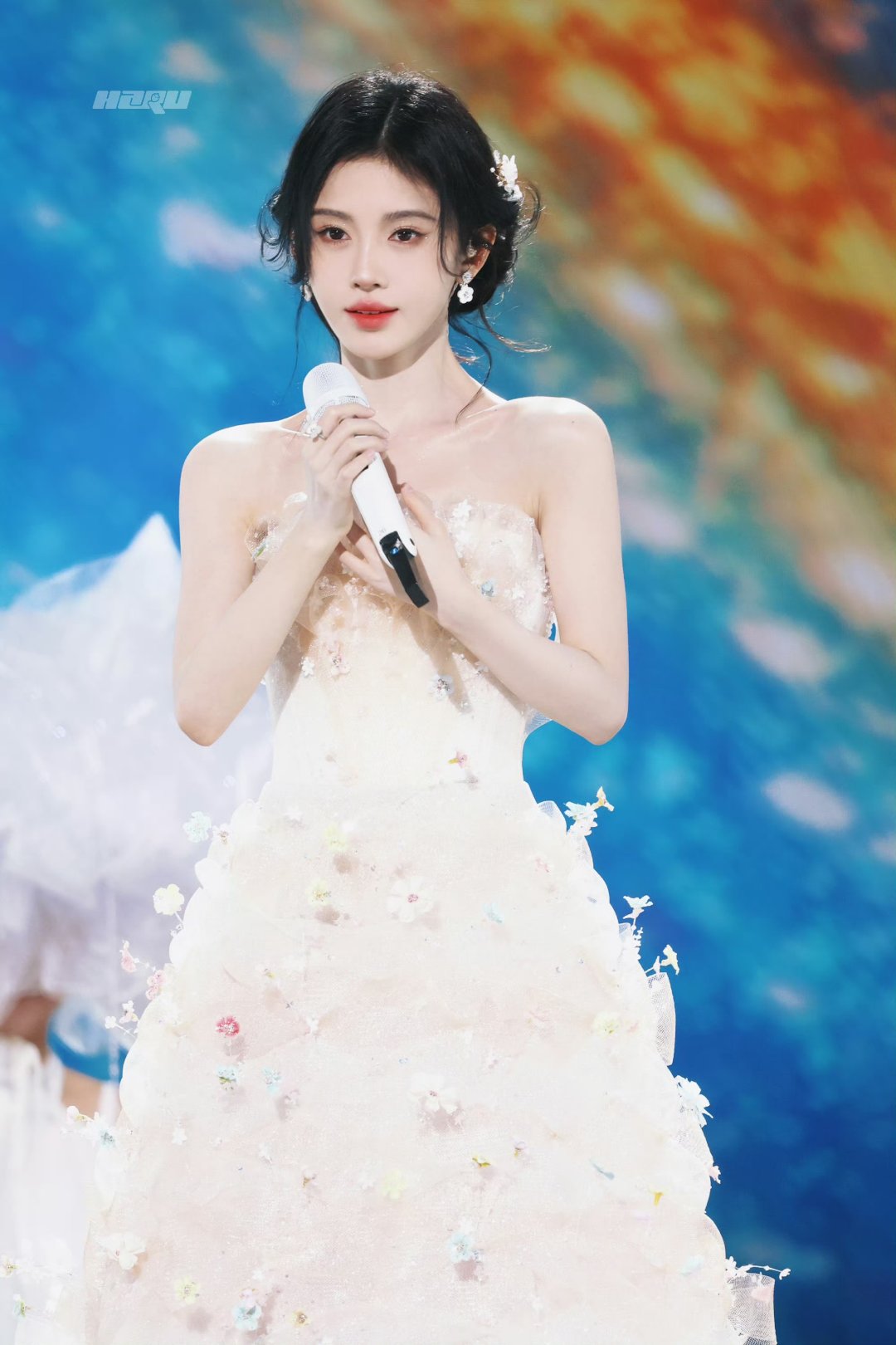 鞠婧祎美如仙子,一袭白裙优雅动人,手持话筒,光彩照人