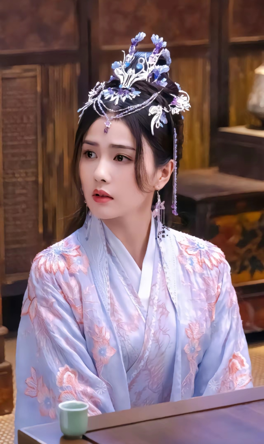 白鹿穿着汉服,头戴精致头饰,静静坐在桌前,仿佛穿越千年,回到古代闺阁