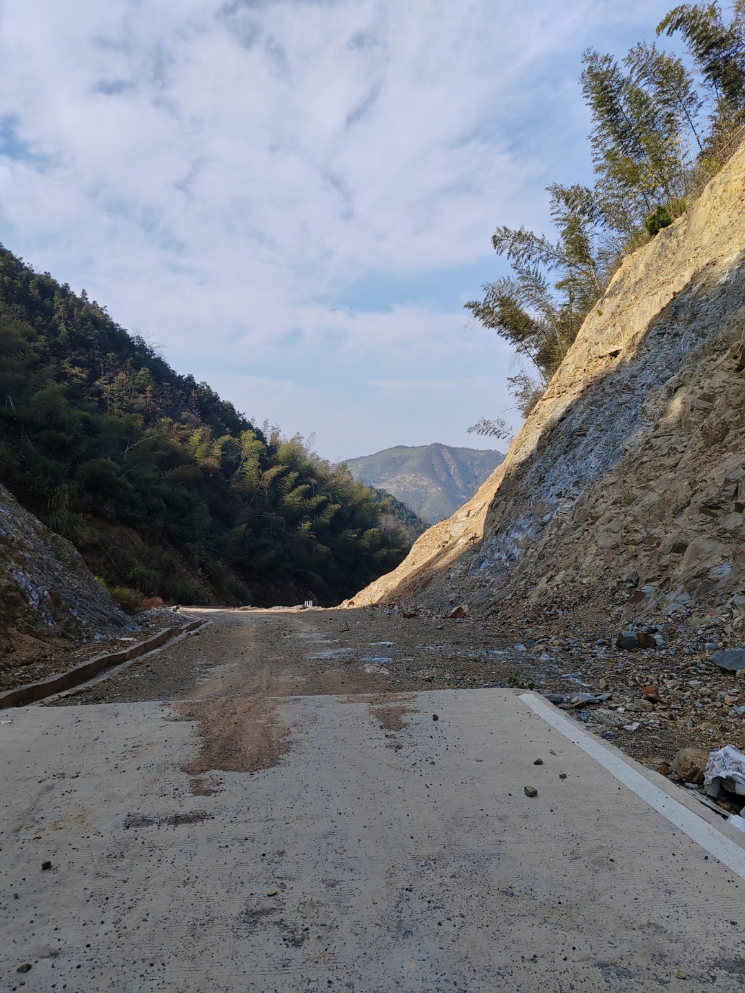 刚下过雨的山区道路,泥泞难行,两旁树木葱郁,远处