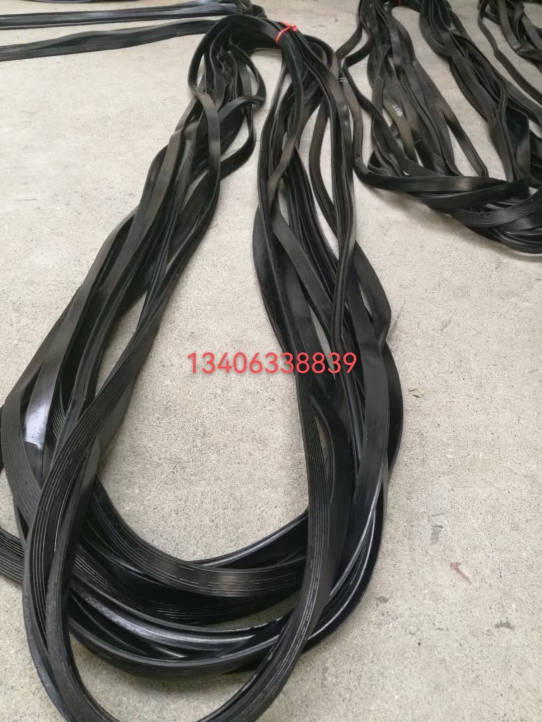 这些长长的黑色橡胶带,整齐地摆放在混凝土地面上,看起来像是准备用于