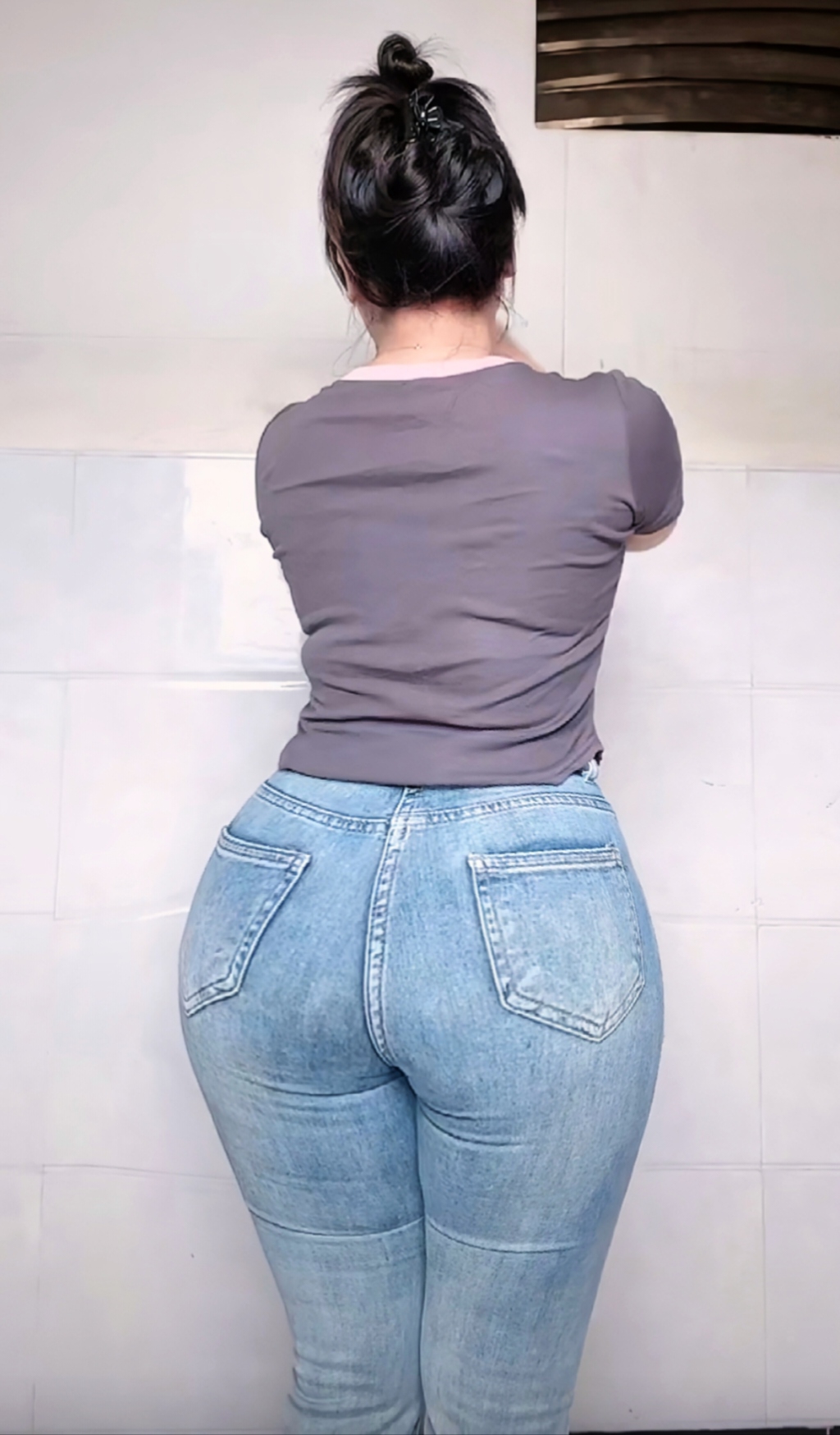 紧身牛仔裤勾勒出她圆润的臀部,红色背心更添几分热情.