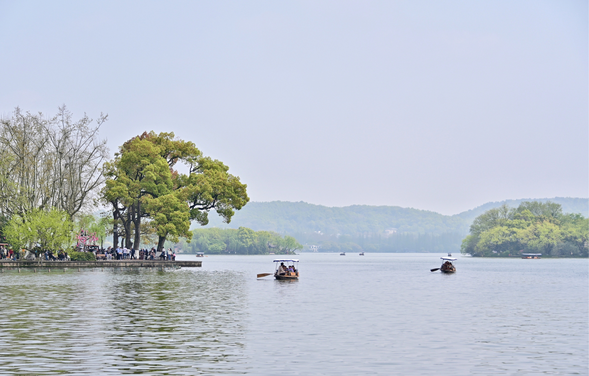 静谧的湖面上,几艘小船悠然自得地行驶着,随着清风的拂面,船帆在湖面