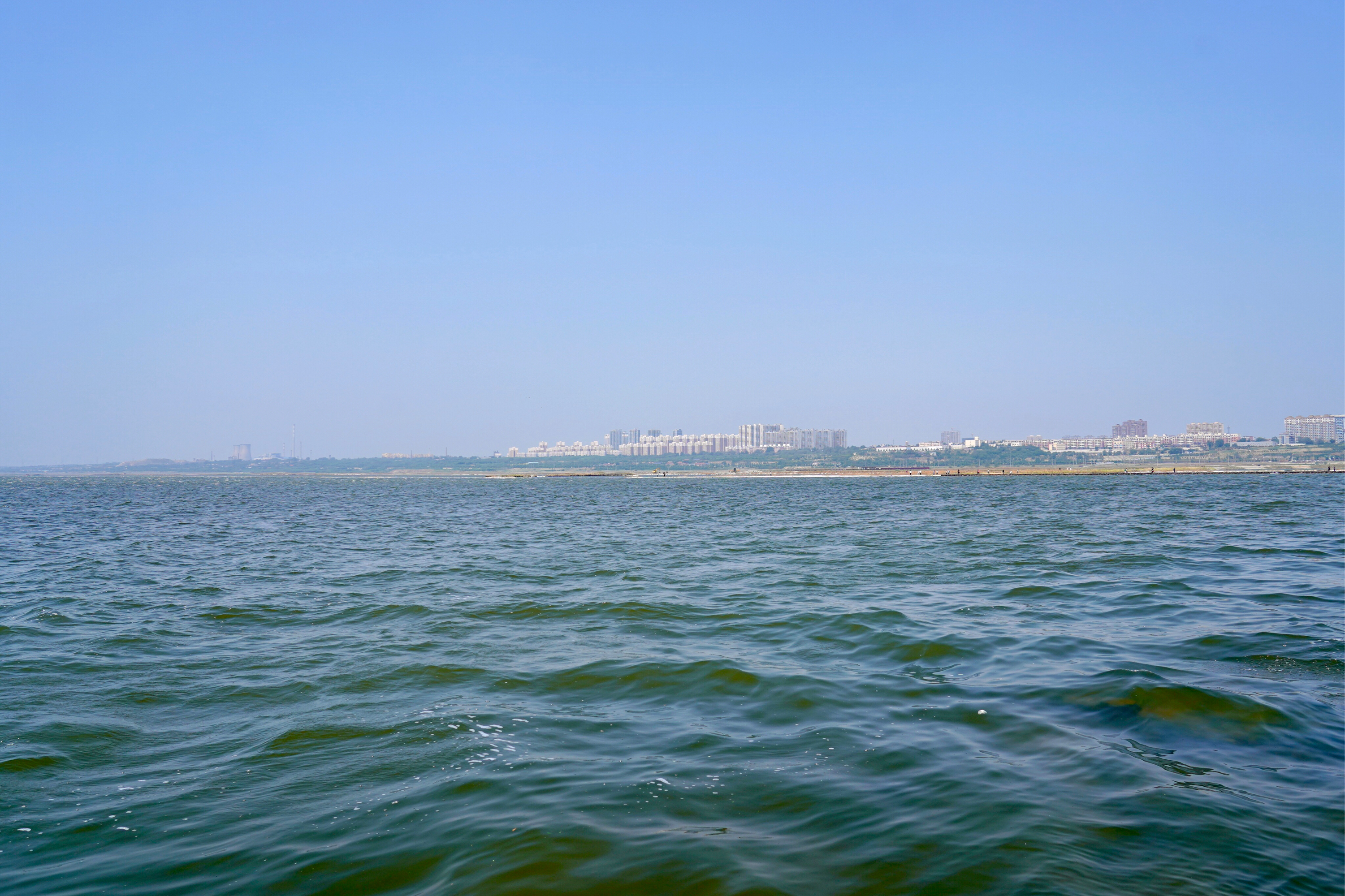 水面深蓝水面深蓝水面深蓝,波光粼粼,远处的城市建筑群洁白无瑕,宛如