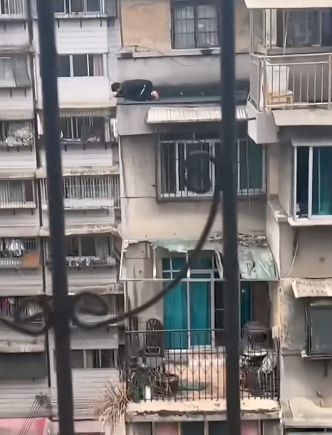 楼下吵架,男子凑热闹趴在顶楼边缘看,看得对面邻居心惊胆颤的