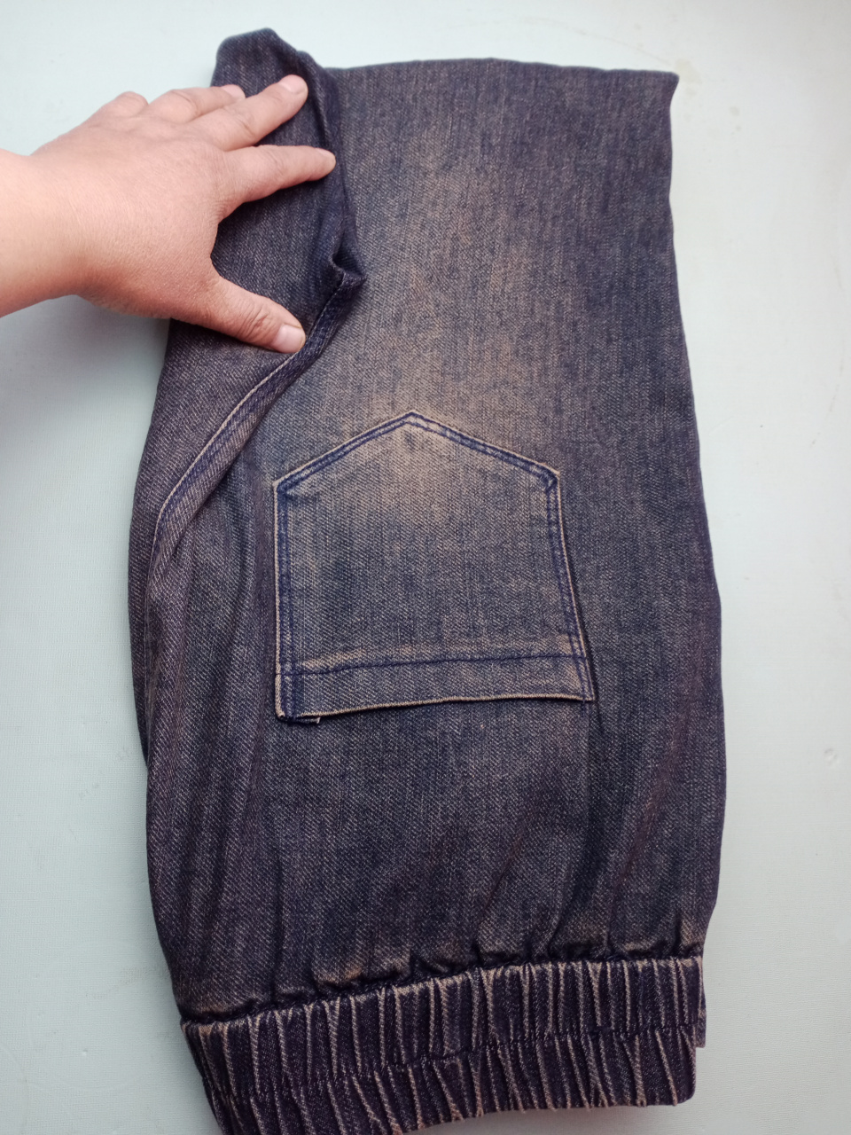 把牛仔裤平铺,两条裤腿向上折,然后再对折,再把裤裆的部位向里折一点.