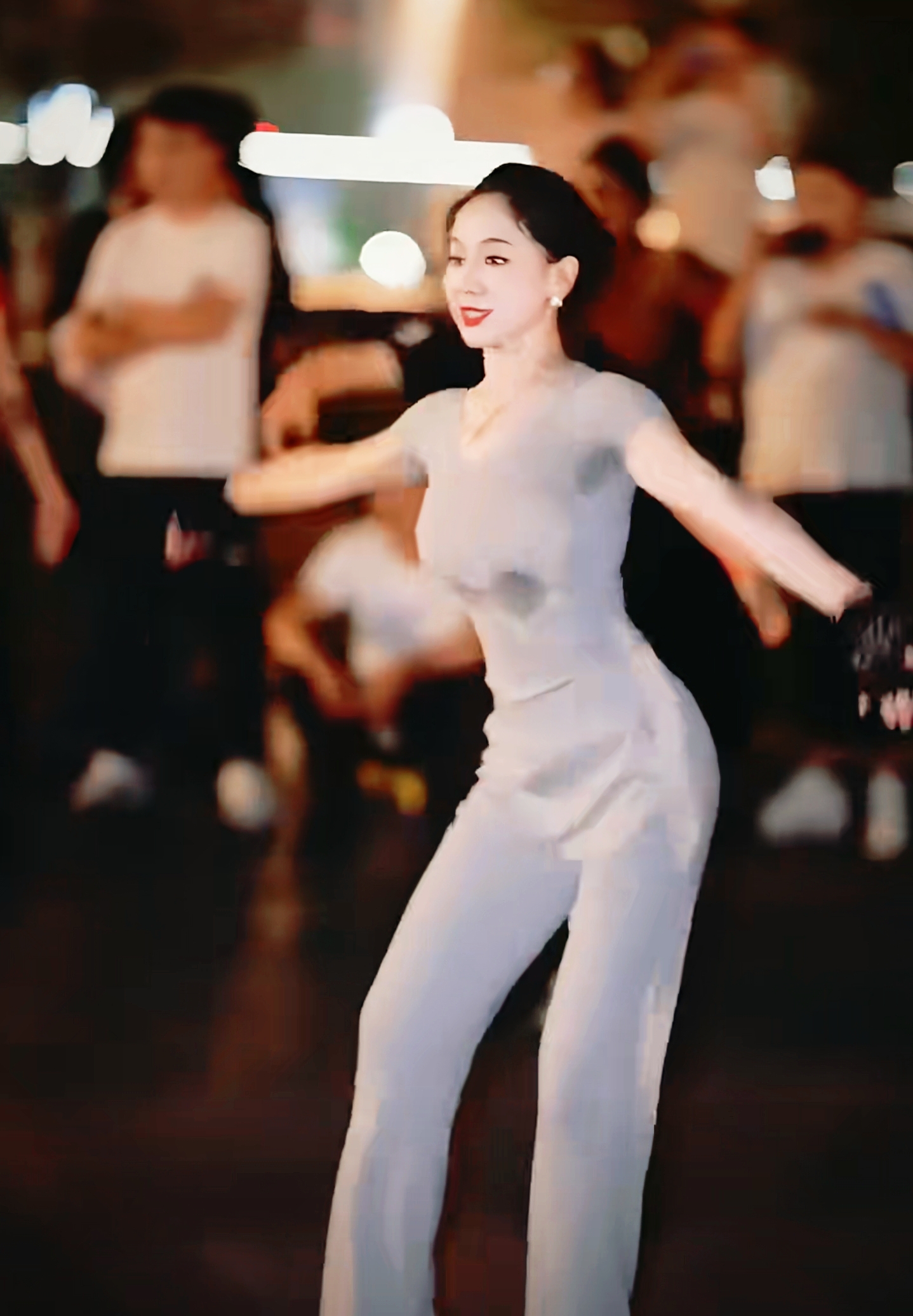 炎热的夜晚,一群人在街头赏心悦目看美女跳舞,她的笑容如月光般迷人