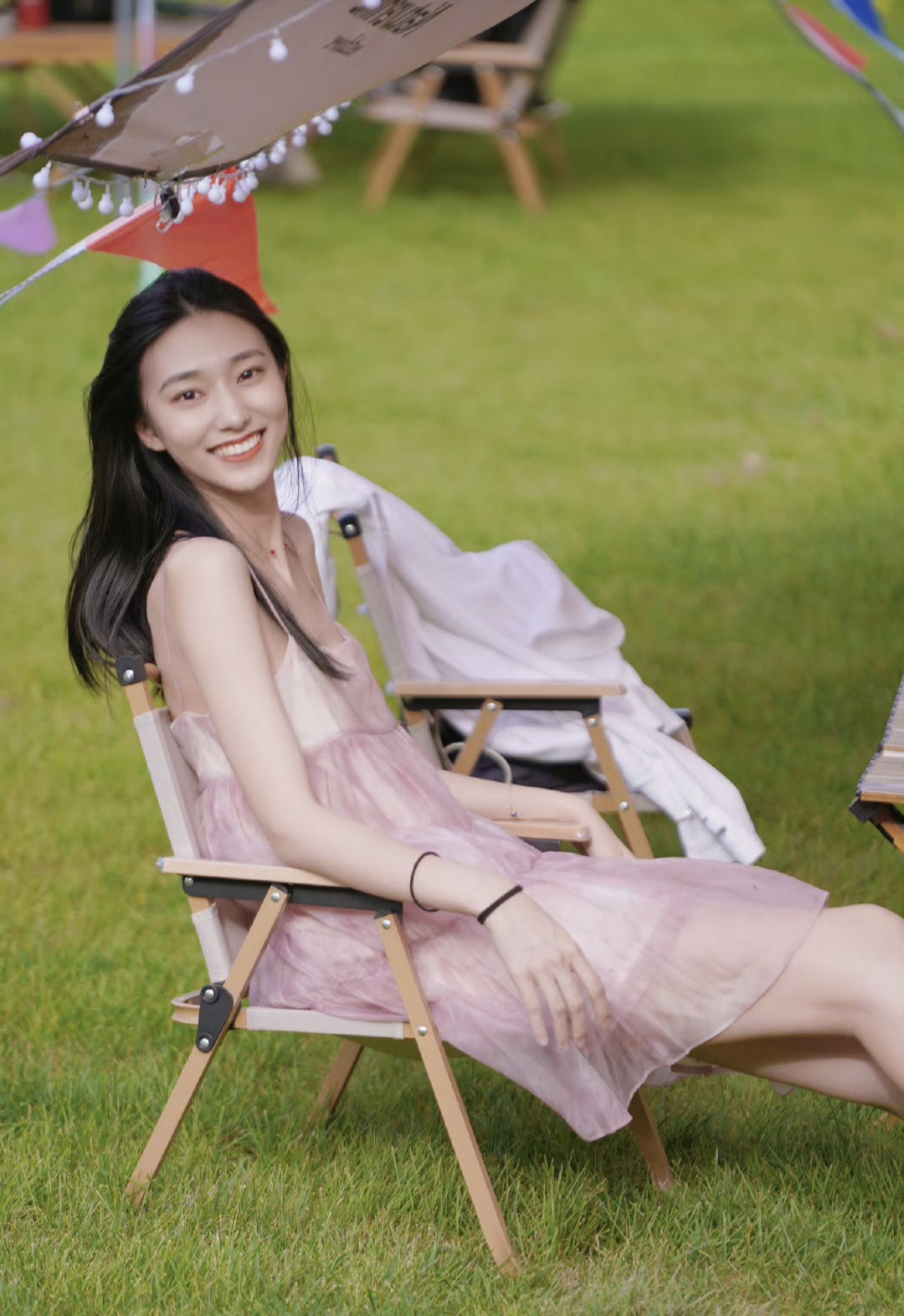 美女坐在绿茵草坪上笑容灿烂享受着轻松愉快的时光