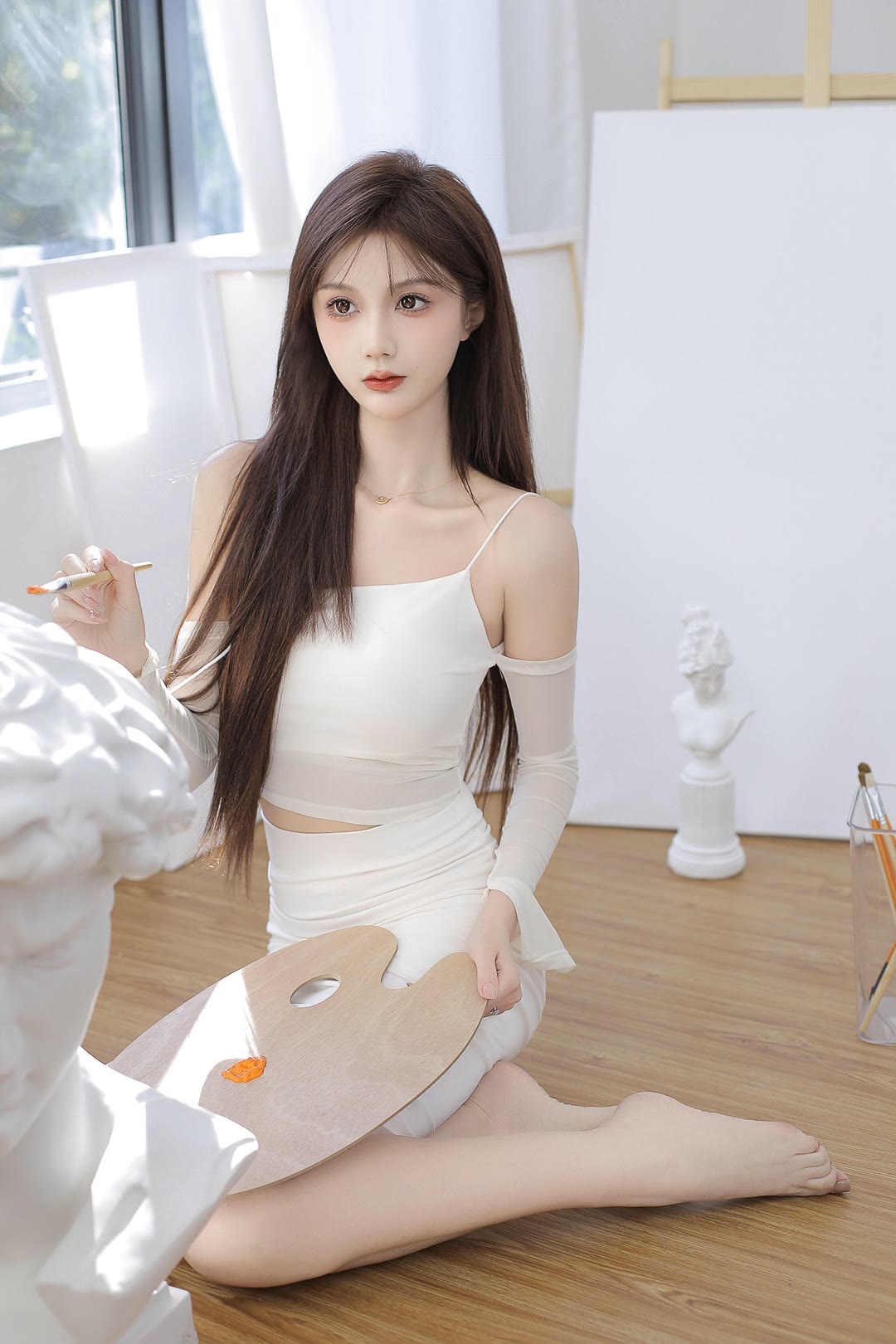 白色的吊带裙,搭配一双丝袜.坐在阳台边的沙发上