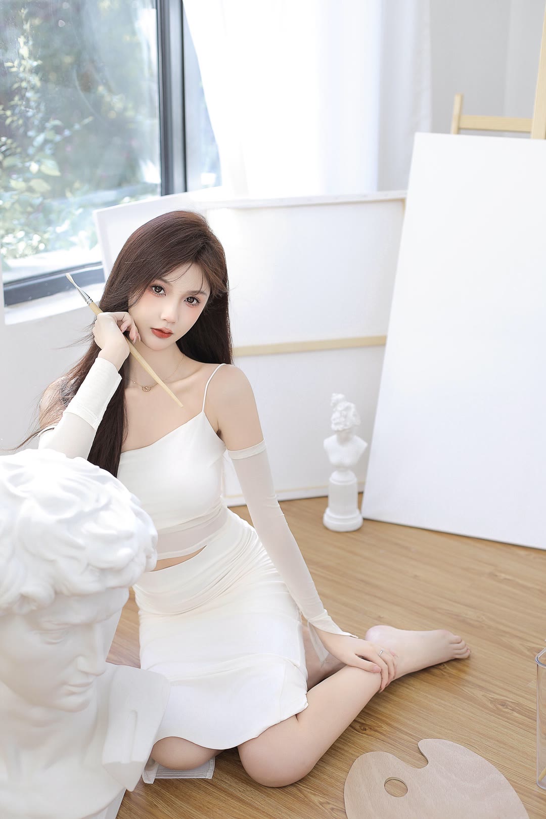 白色的吊带裙,搭配一双丝袜.坐在阳台边的沙发上